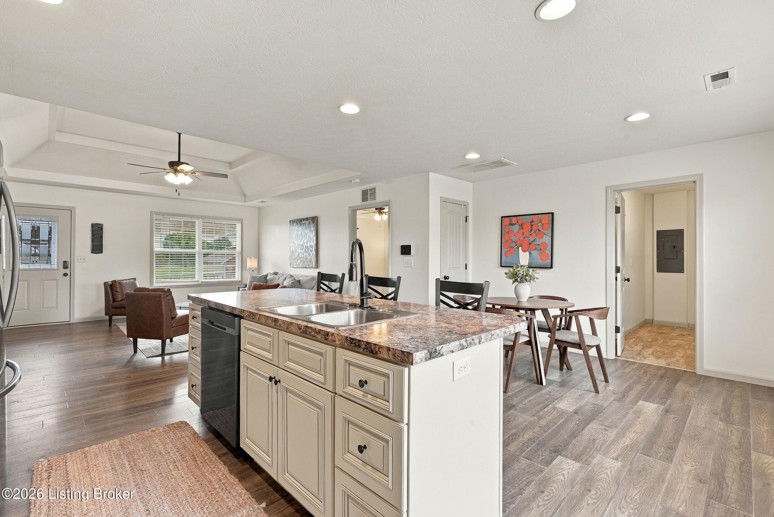 Open-plan kitchen with a large stone-counter island, adjoining dining area, and vaulted ceiling.