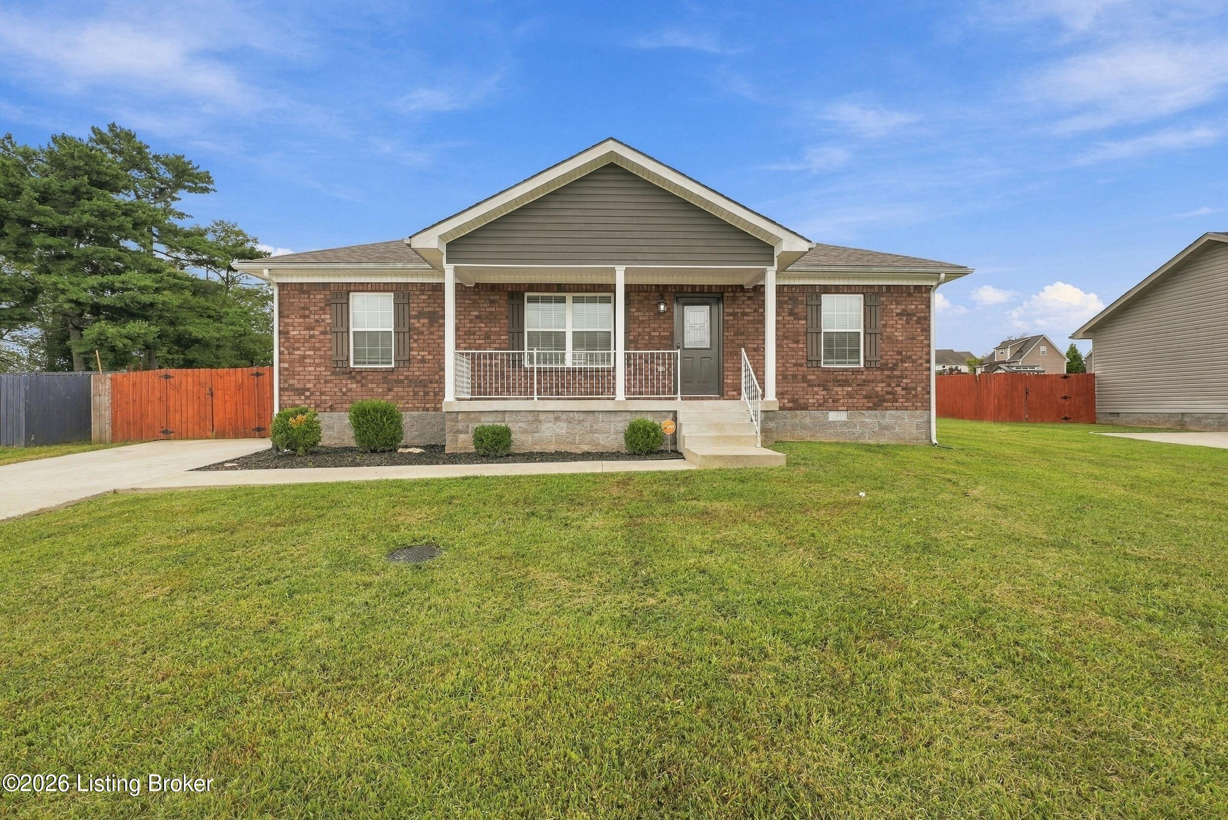 Brick house with a covered front porch, white railings, and a broad lawn.