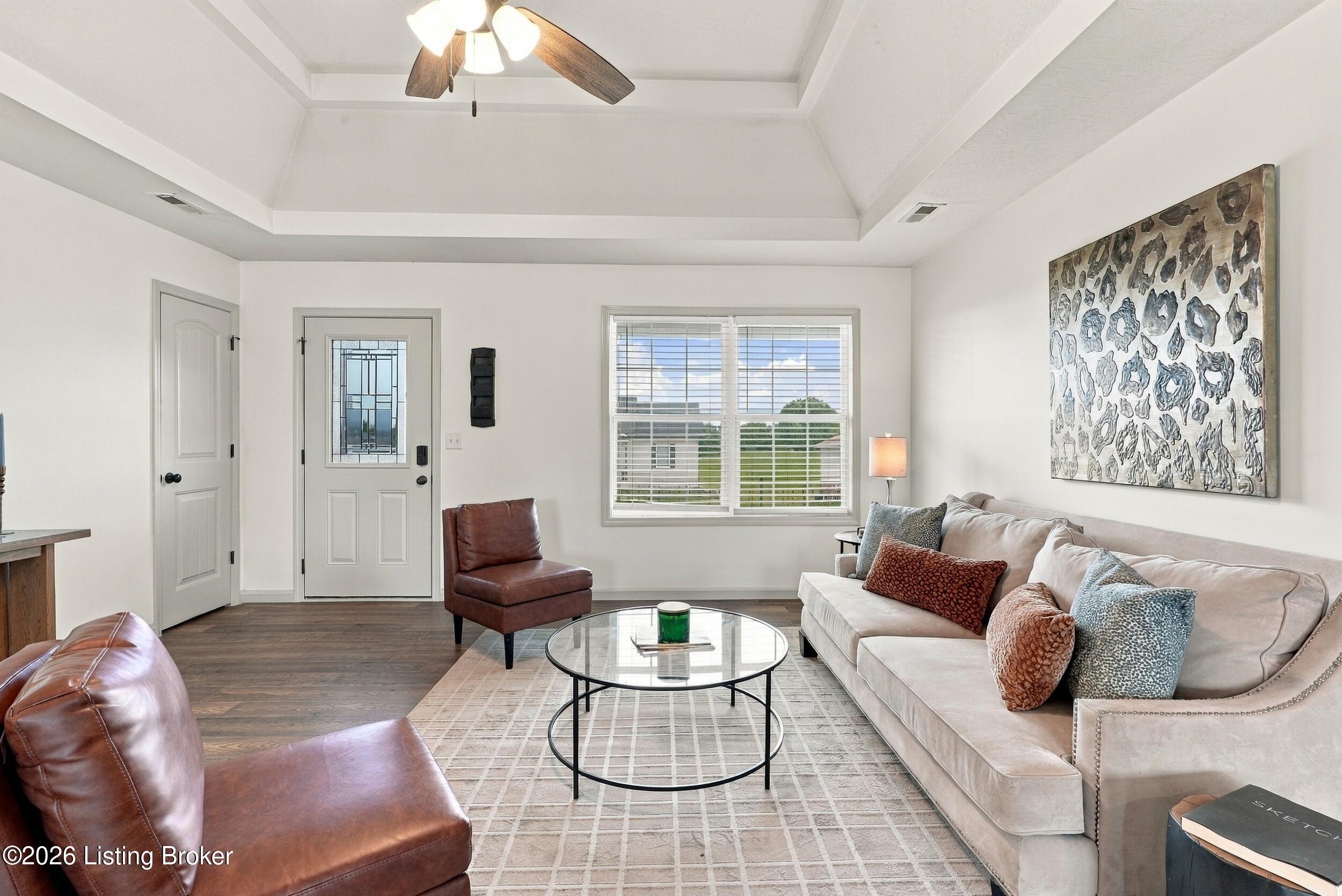 Furnished living room with a tray ceiling, leather chairs, and a large window.