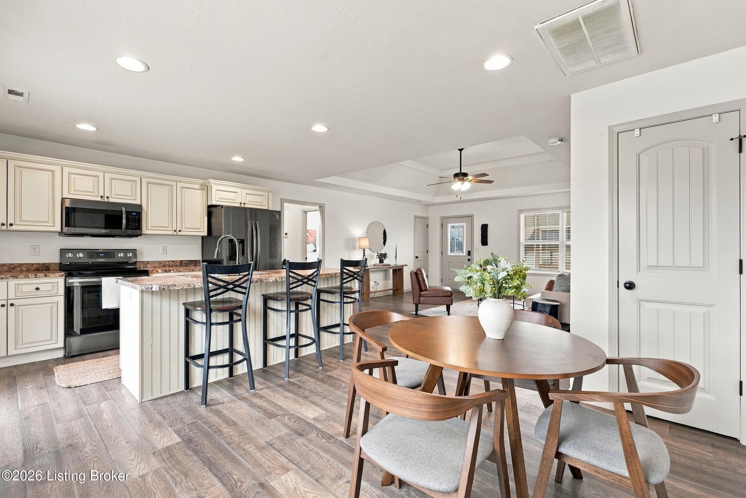 Open-plan kitchen and dining area with a breakfast island, stainless appliances, and round wooden table.