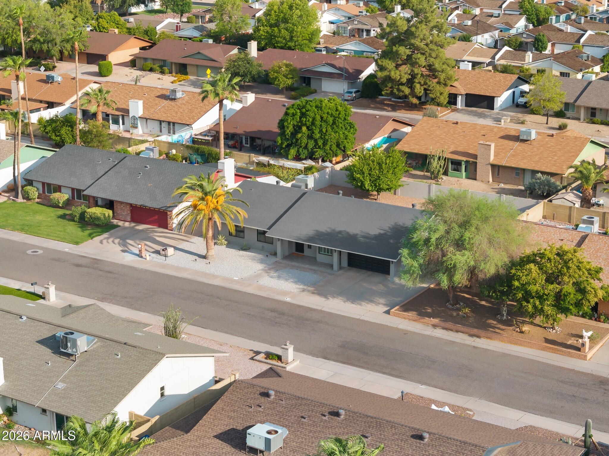 Single-story gray house with a red garage door and palm tree, viewed from above.