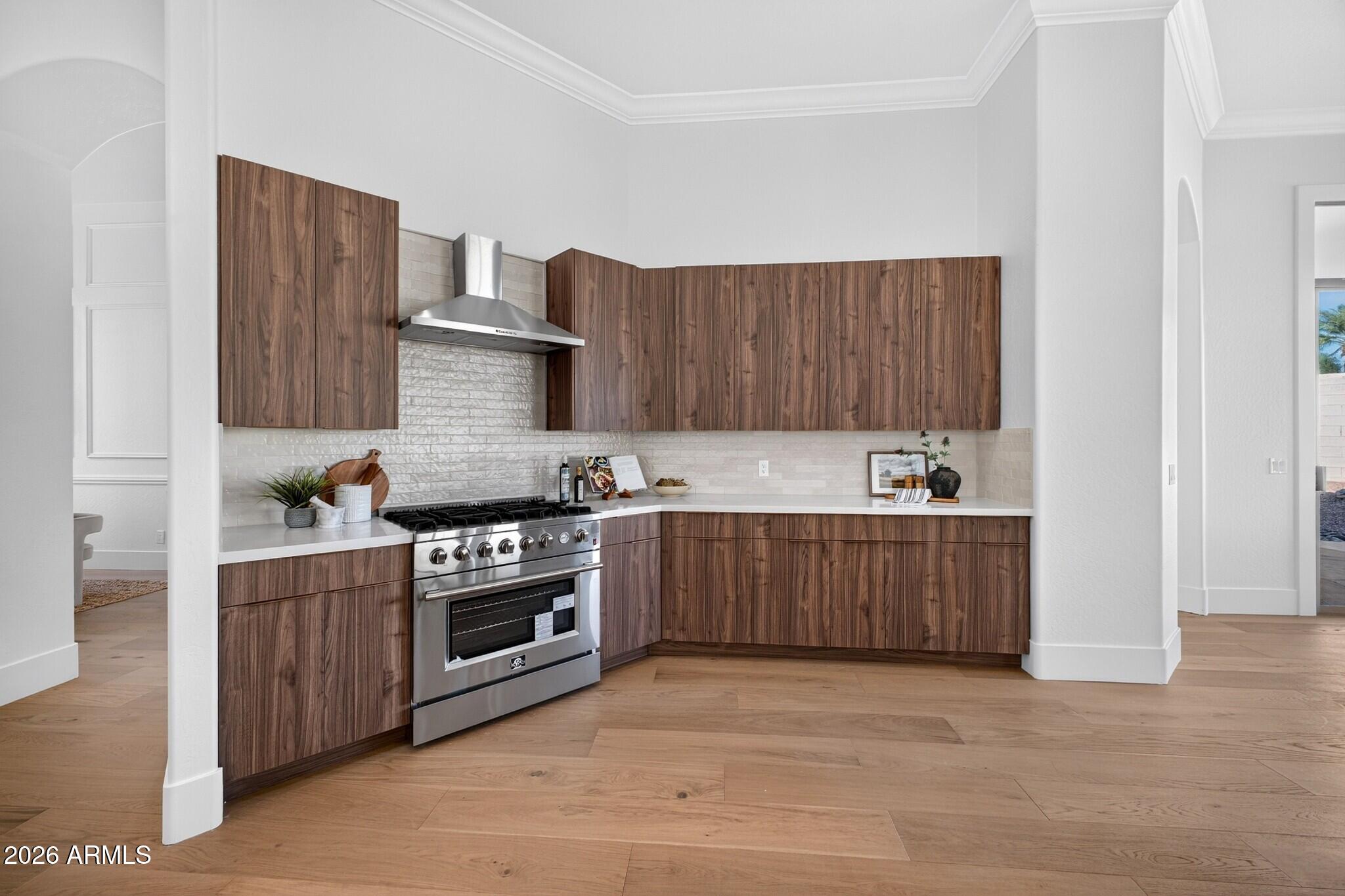 Kitchen with walnut cabinets, a stainless-steel range, white counters, and wide-plank wood flooring.