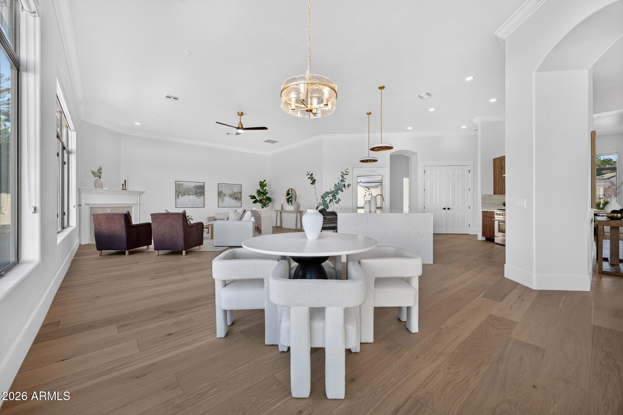 Open-plan dining room with a round table, white chairs, and a living area with fireplace beyond.