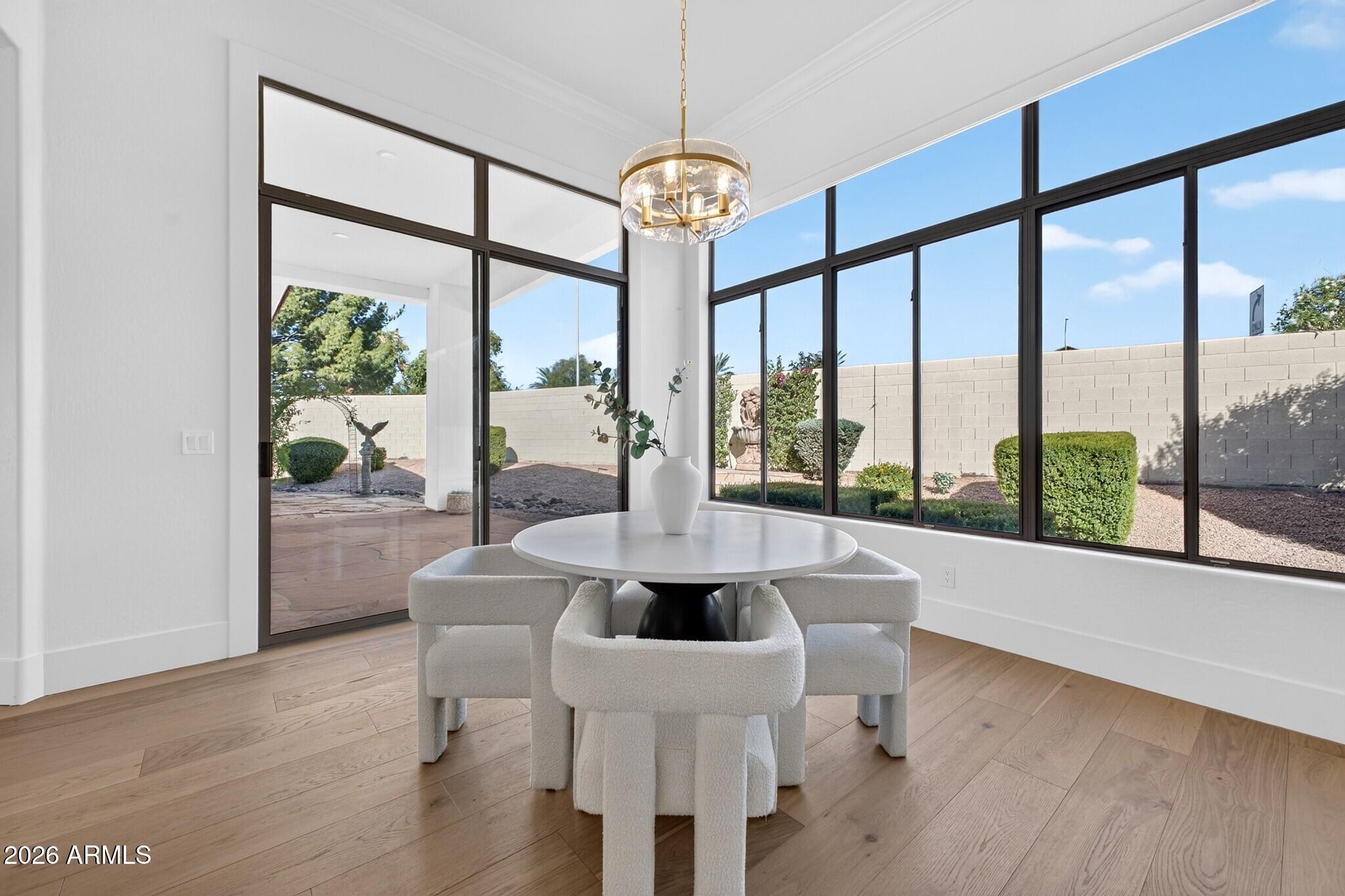 Dining area with a round white table, sculptural chairs, and expansive windows overlooking the yard.
