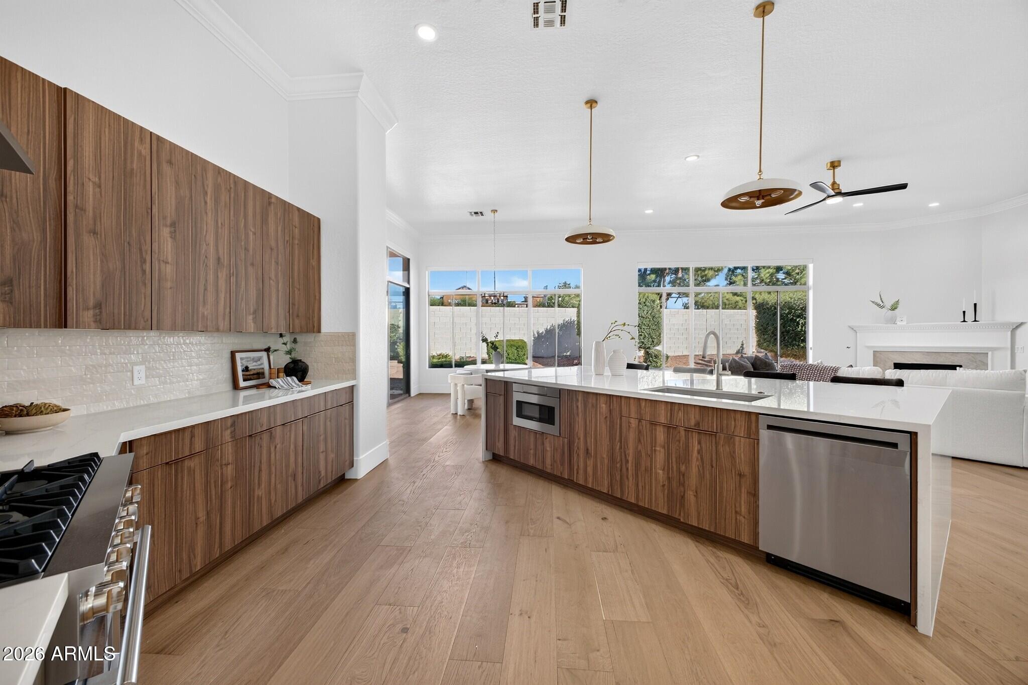 Open-plan kitchen with walnut cabinets, a large white island, and windows overlooking the backyard.