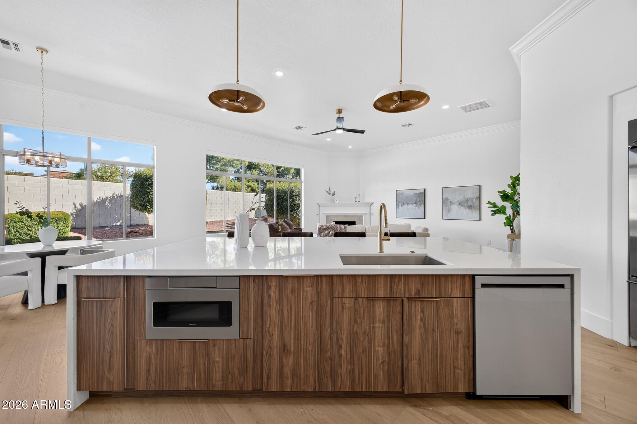 Open-plan kitchen with a large white island, walnut cabinetry, and views into the living room.