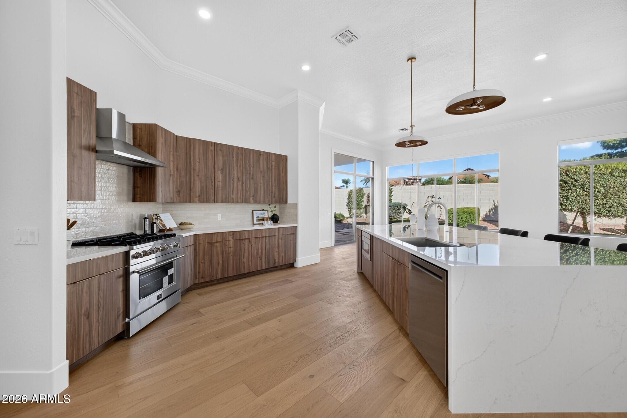 Modern kitchen with walnut cabinets, a large white island, and windows overlooking the backyard.