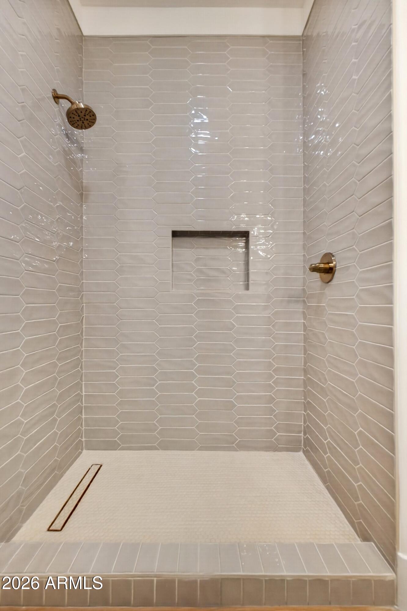 Walk-in shower with glossy gray tile, a recessed niche, bronze fixtures, and a linear floor drain.