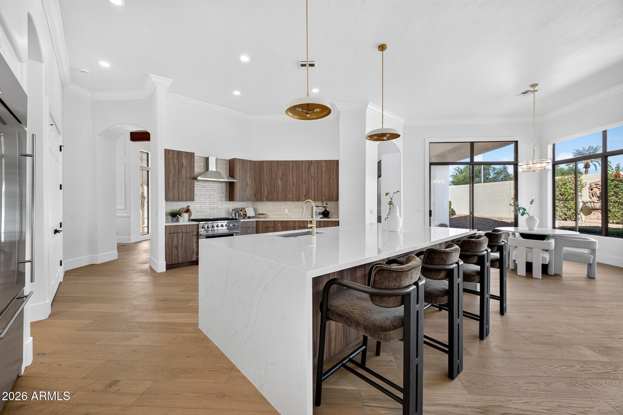 Open kitchen with a large white island, wood cabinets, and windows overlooking the backyard.
