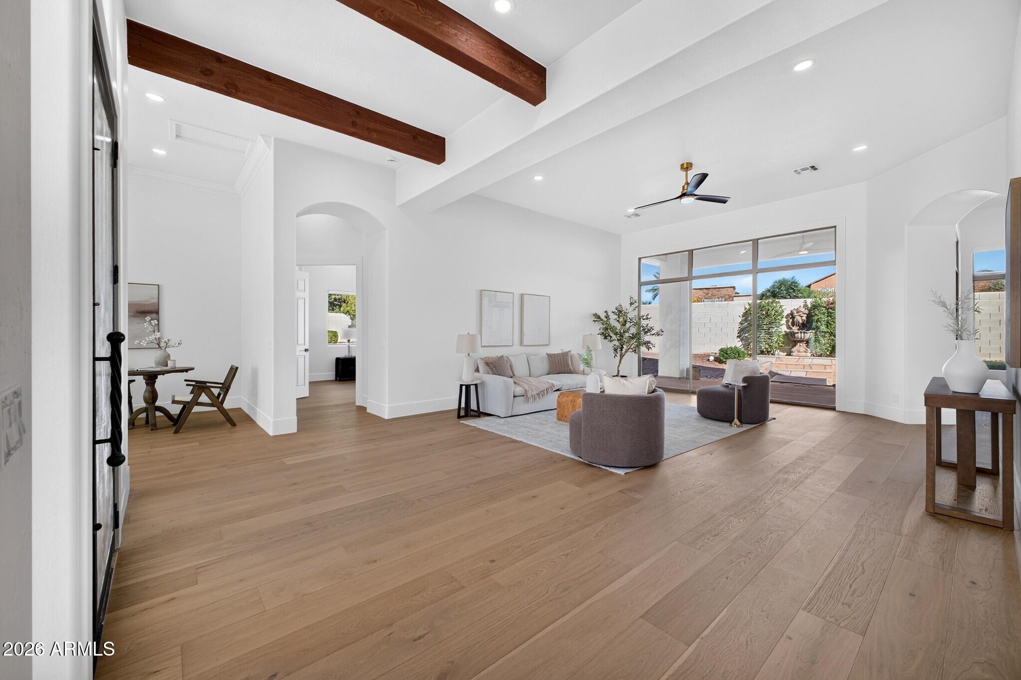 Staged living room with exposed wood beams, light wood floors, and sliding glass doors to a patio.