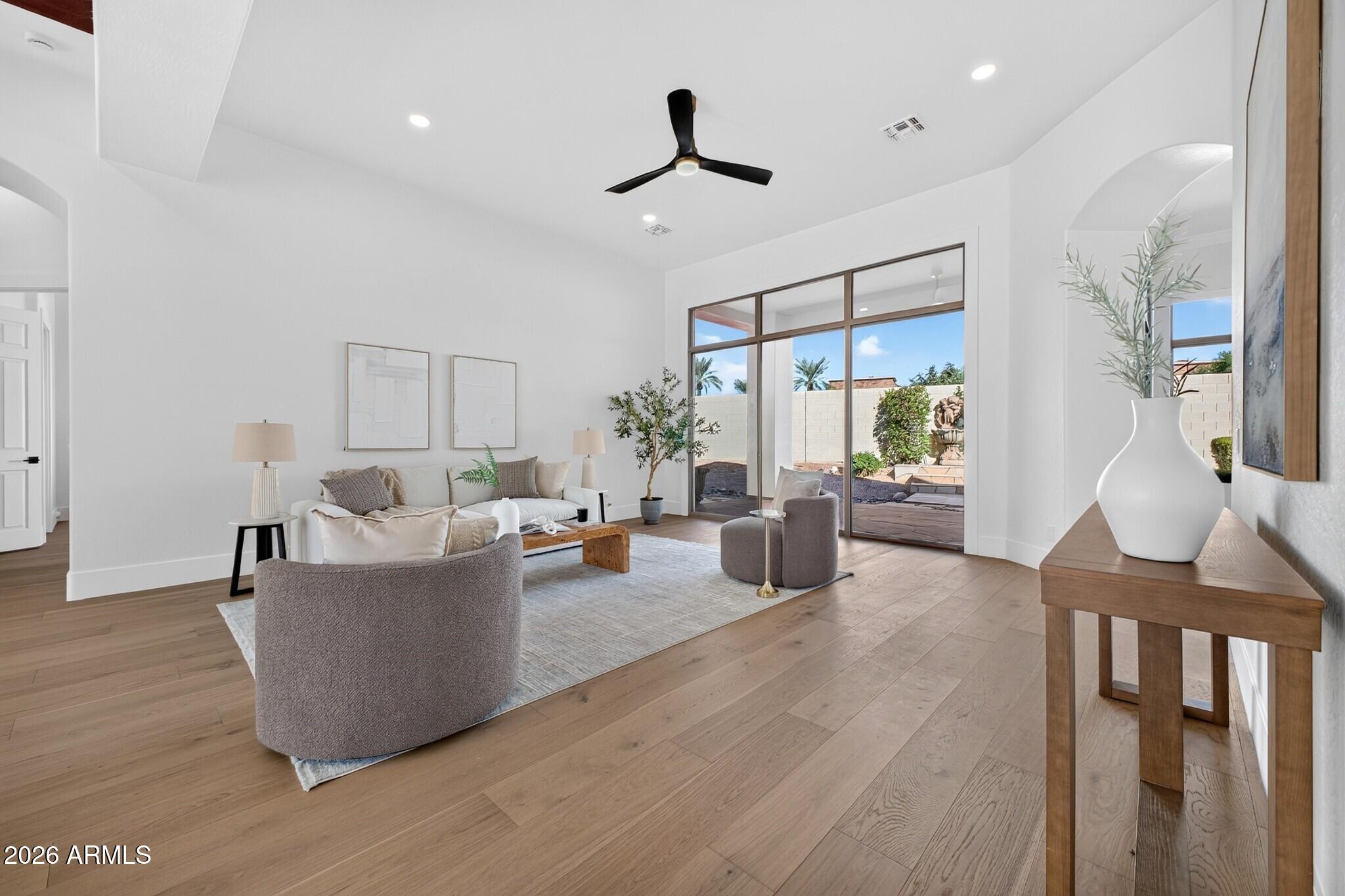 Living room with neutral seating, light wood floors, and large glass doors overlooking a landscaped courtyard.