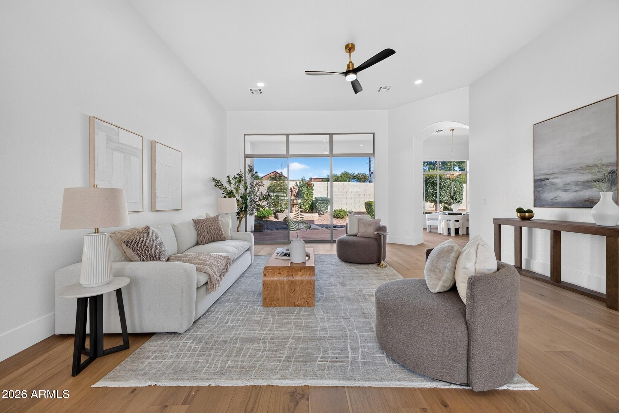 Staged living room with neutral seating, wood floors, and sliding doors to the backyard.