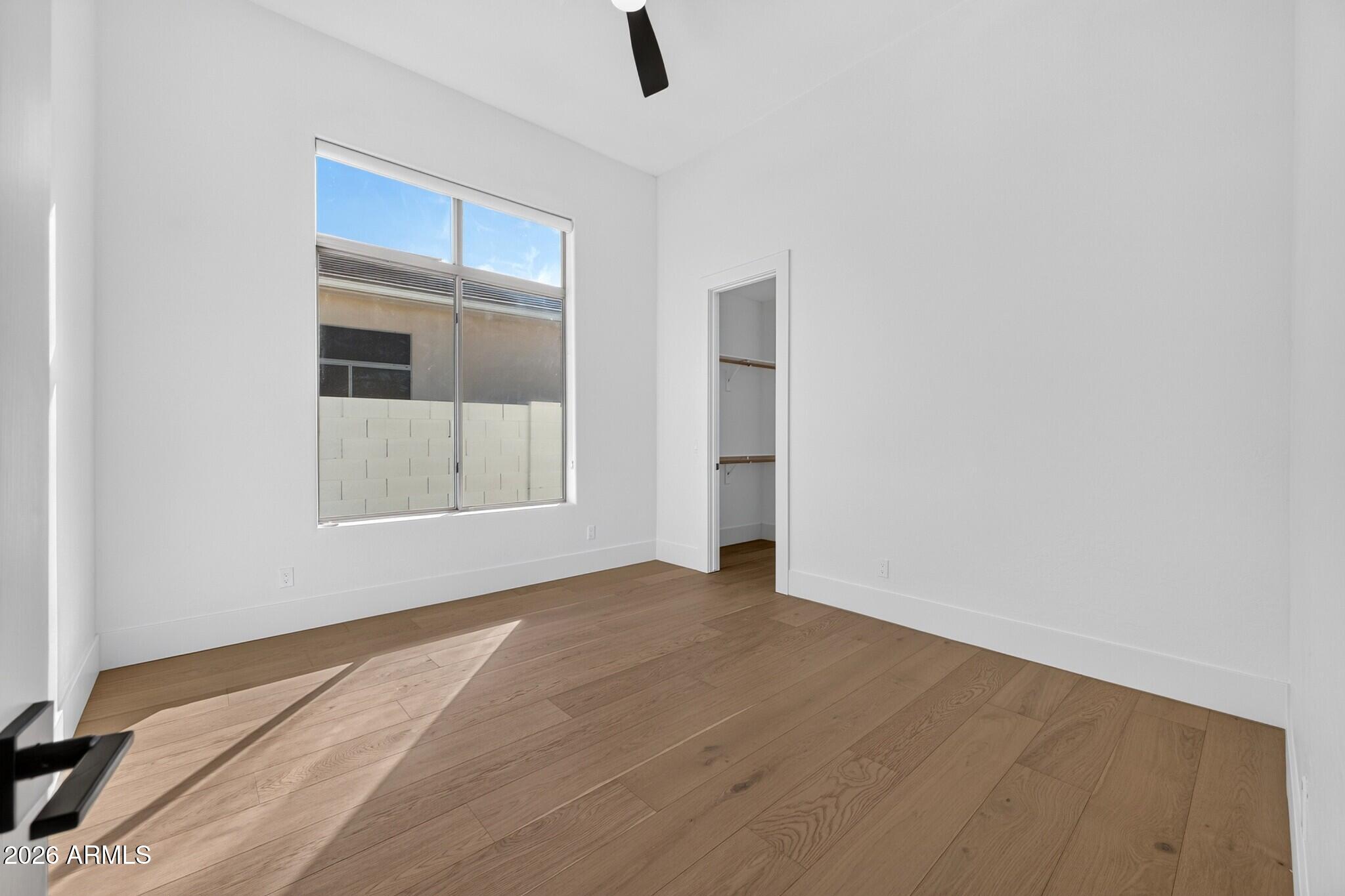 Vacant bedroom with light wood floors, a large window, and an open closet.