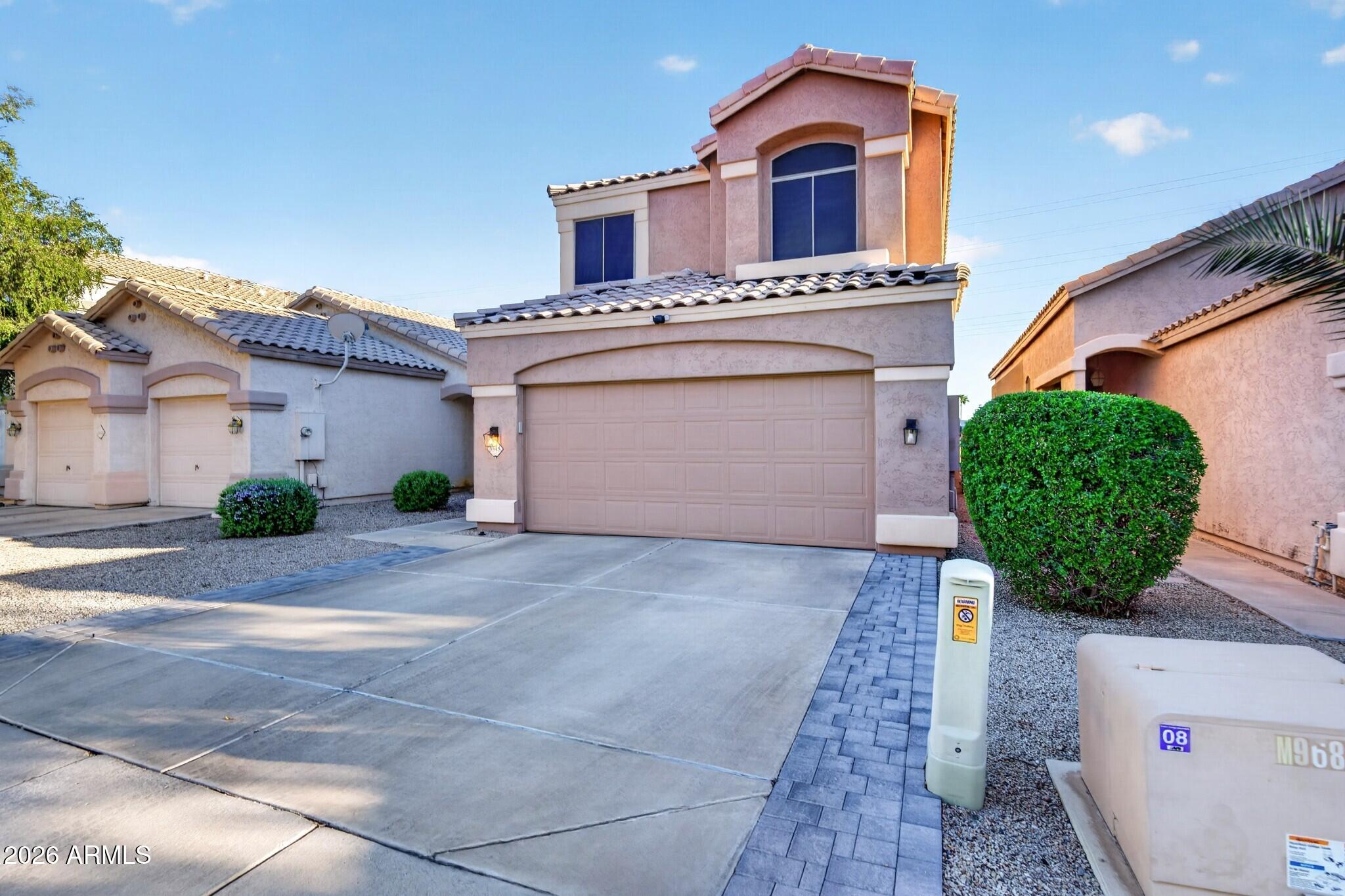 Two-story stucco home with a tiled roof, wide driveway, and attached two-car garage.