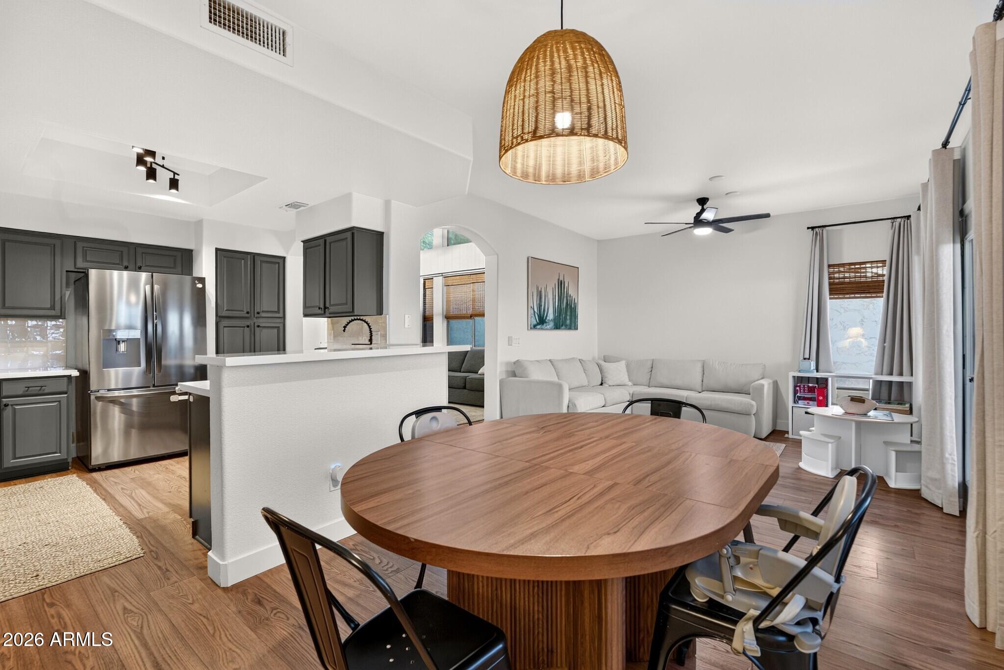 Open-plan kitchen and living room with dark cabinets, a large wood dining table, and a light sectional sofa.