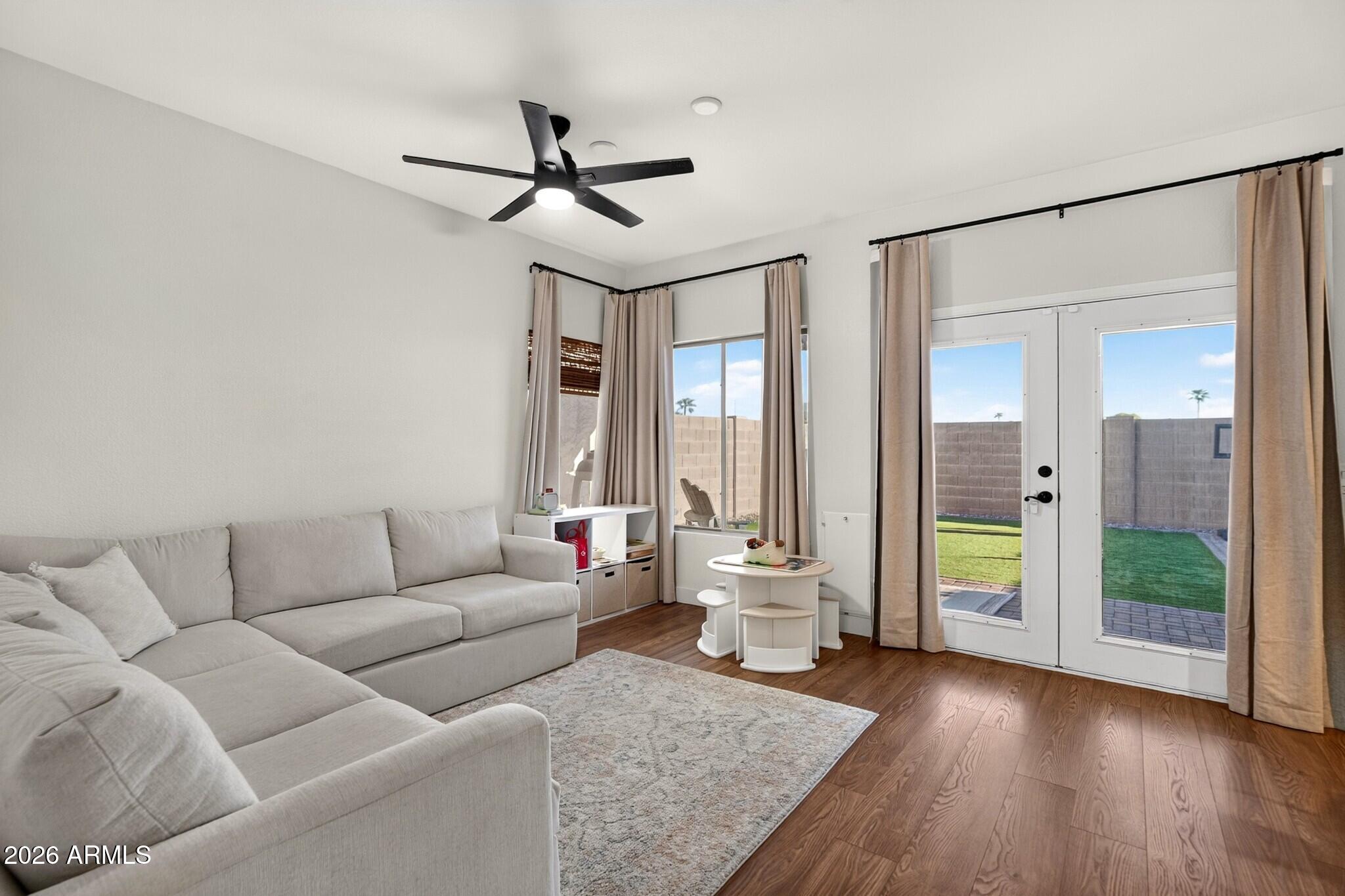 Living room with a light-gray sectional, wood-look floors, and glass doors to the fenced backyard.