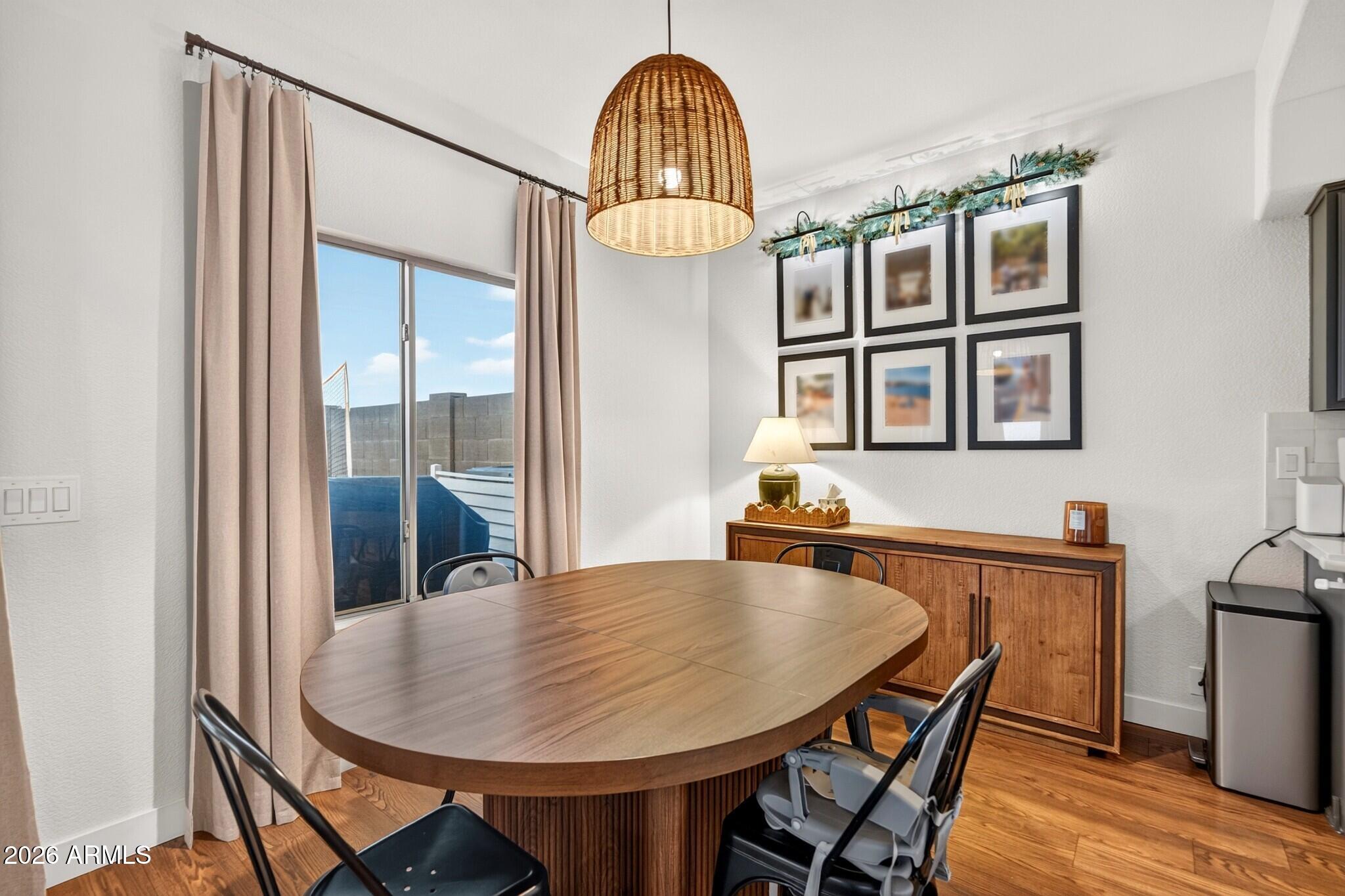 Dining room with an oval wood table, woven pendant light, and sliding glass doors to a patio.
