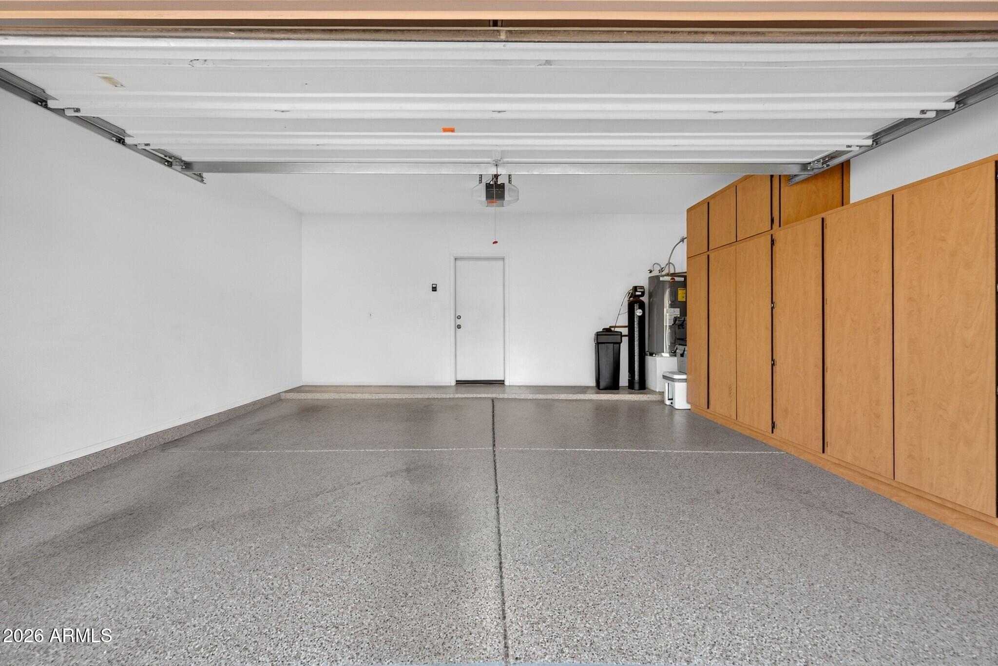 Empty garage with a speckled floor and tall wood storage cabinets along one wall.