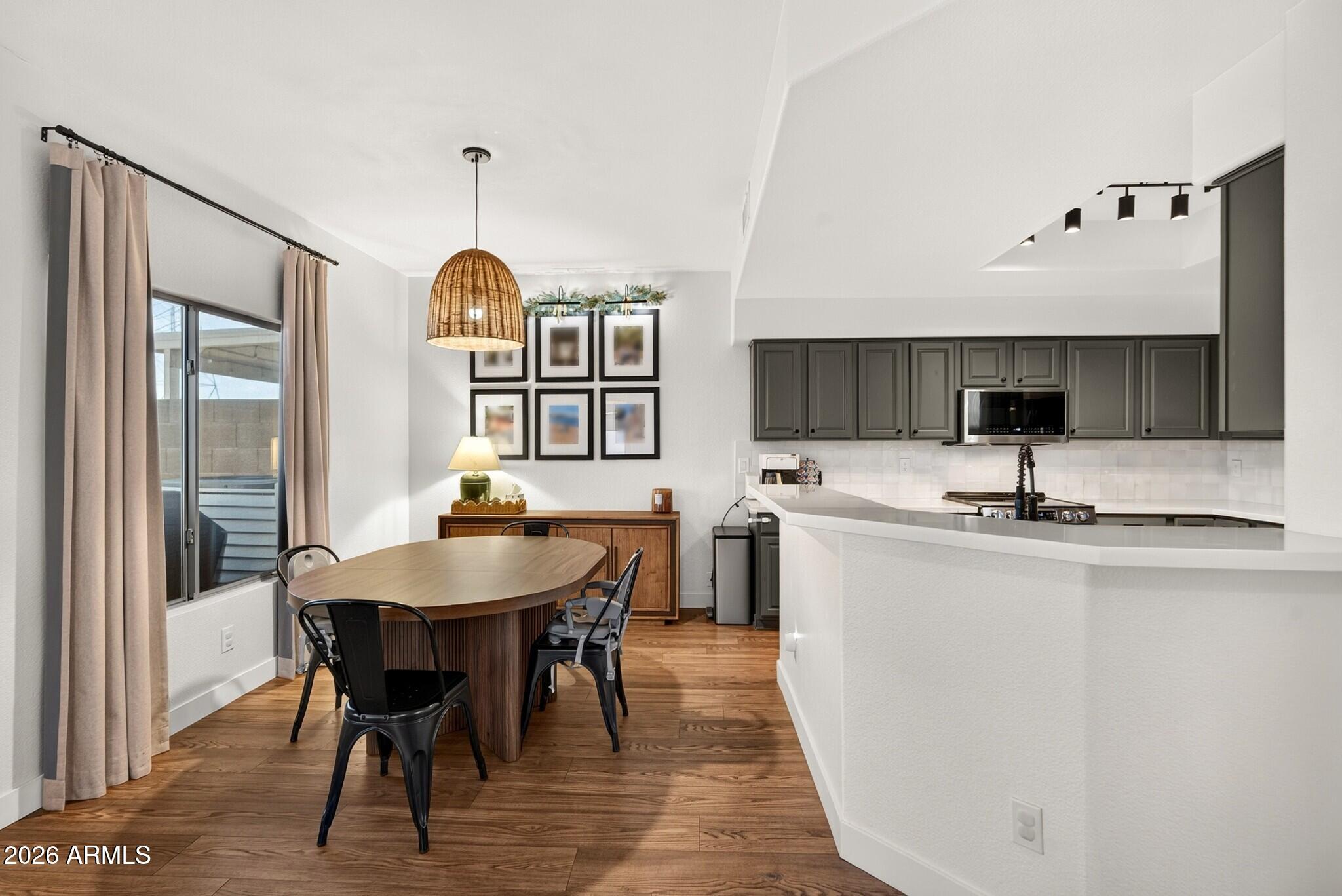 Open kitchen and dining area with dark cabinets, a white peninsula, and an oval wood table.