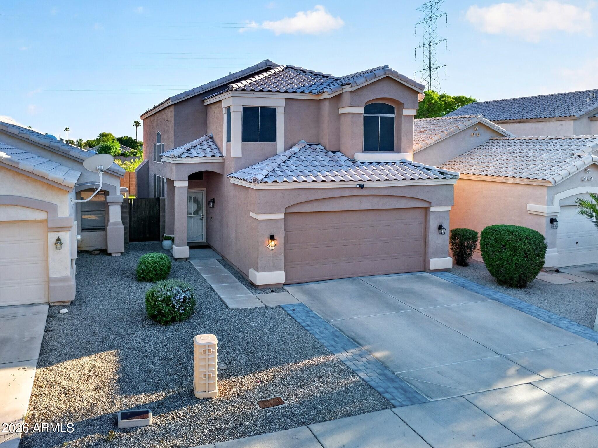 Two-story stucco home with a tile roof, arched windows, and a two-car garage.