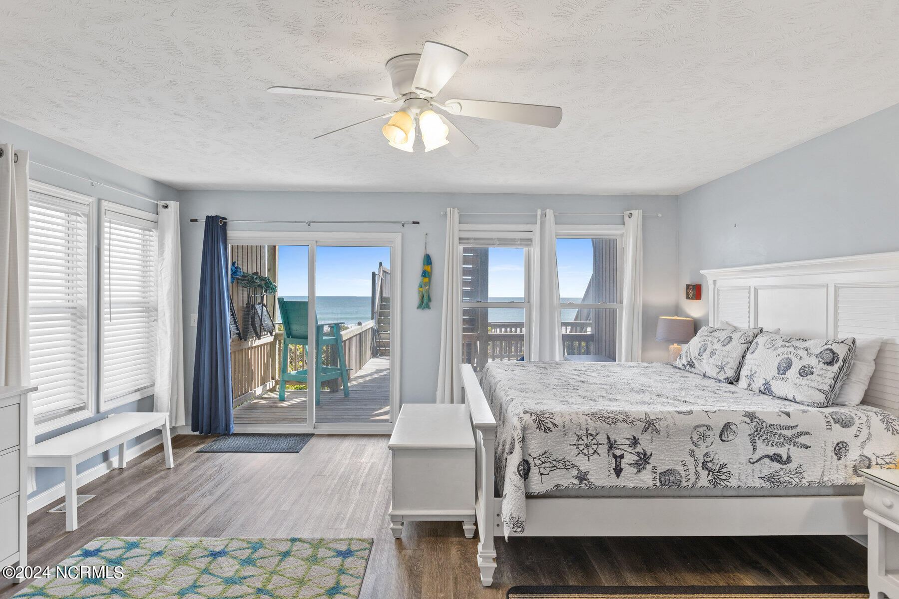 Coastal bedroom with nautical bedding and sliding doors overlooking an oceanfront deck.