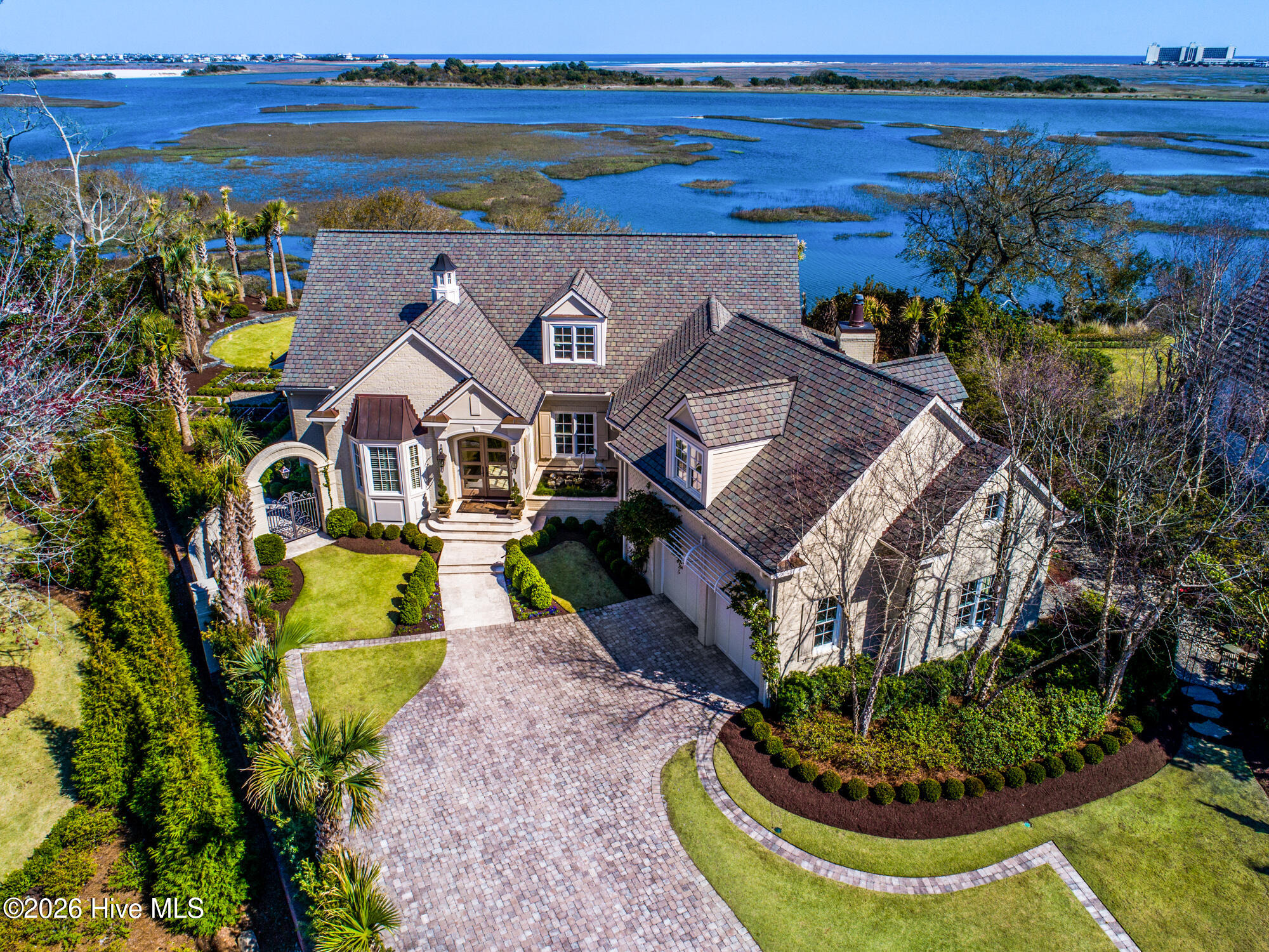 Aerial view of a large landscaped home beside coastal marsh waterways.