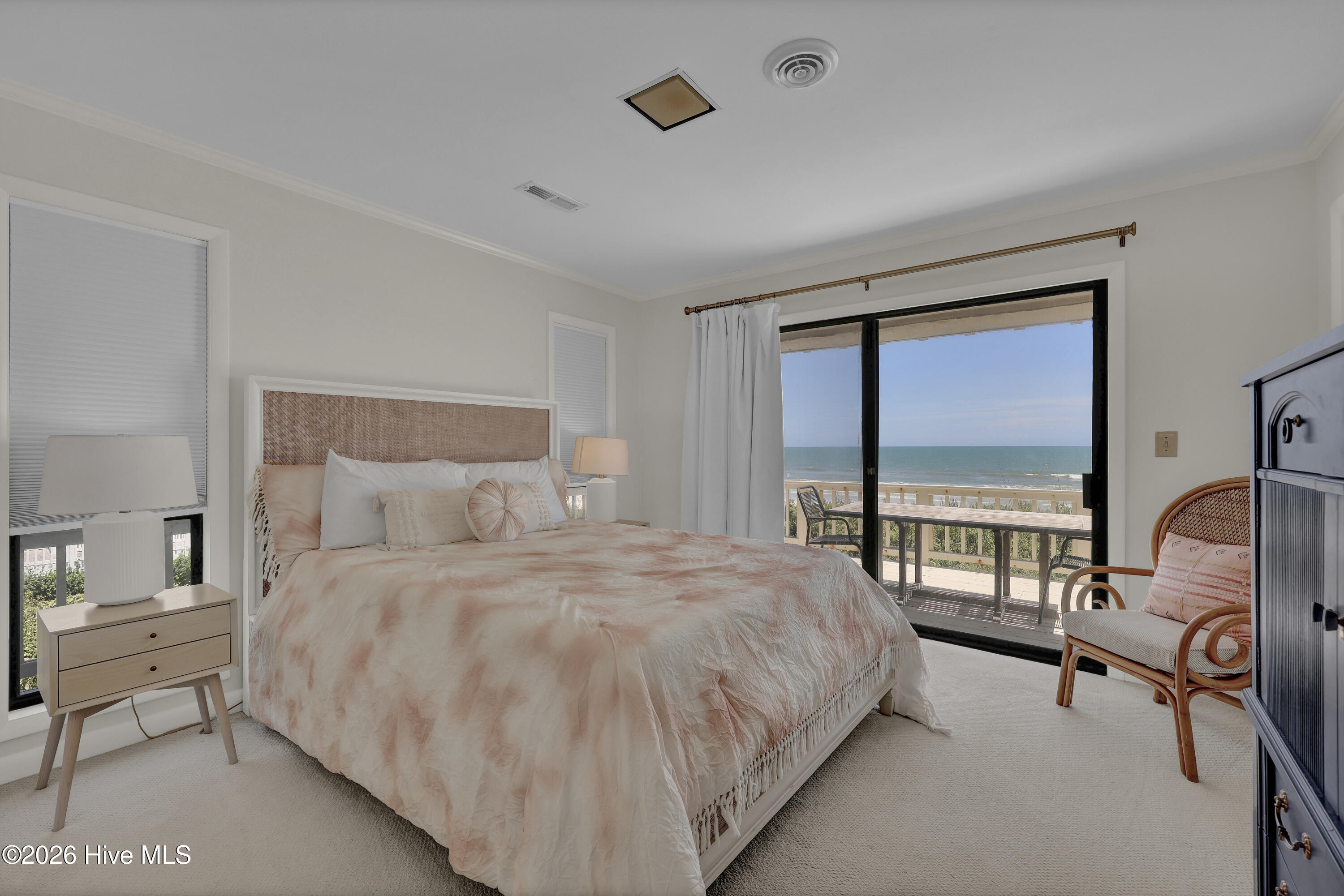 Bedroom with a peach-toned bed and sliding glass doors overlooking the ocean.