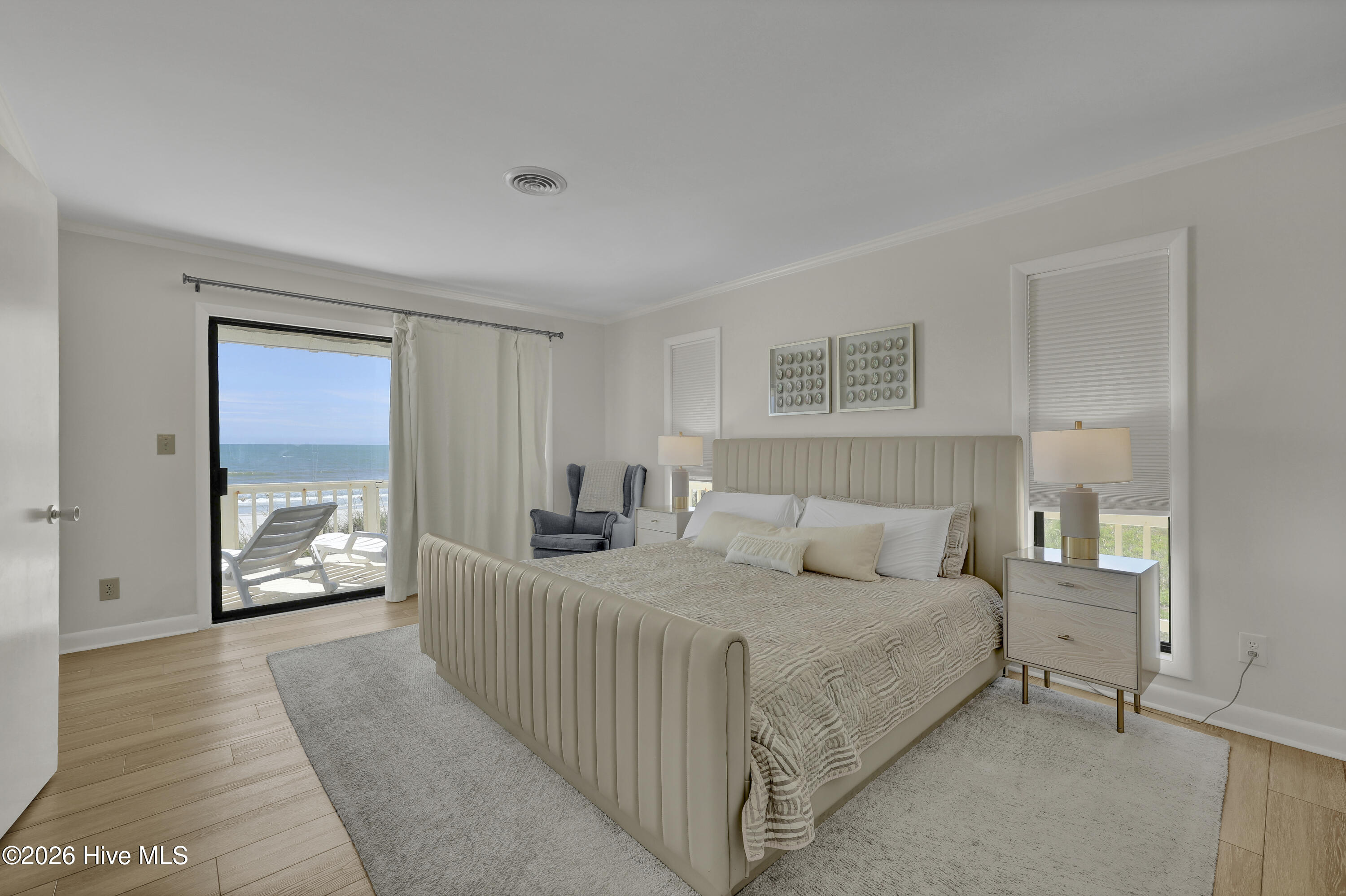 Bedroom with an upholstered bed and sliding glass door overlooking the ocean.