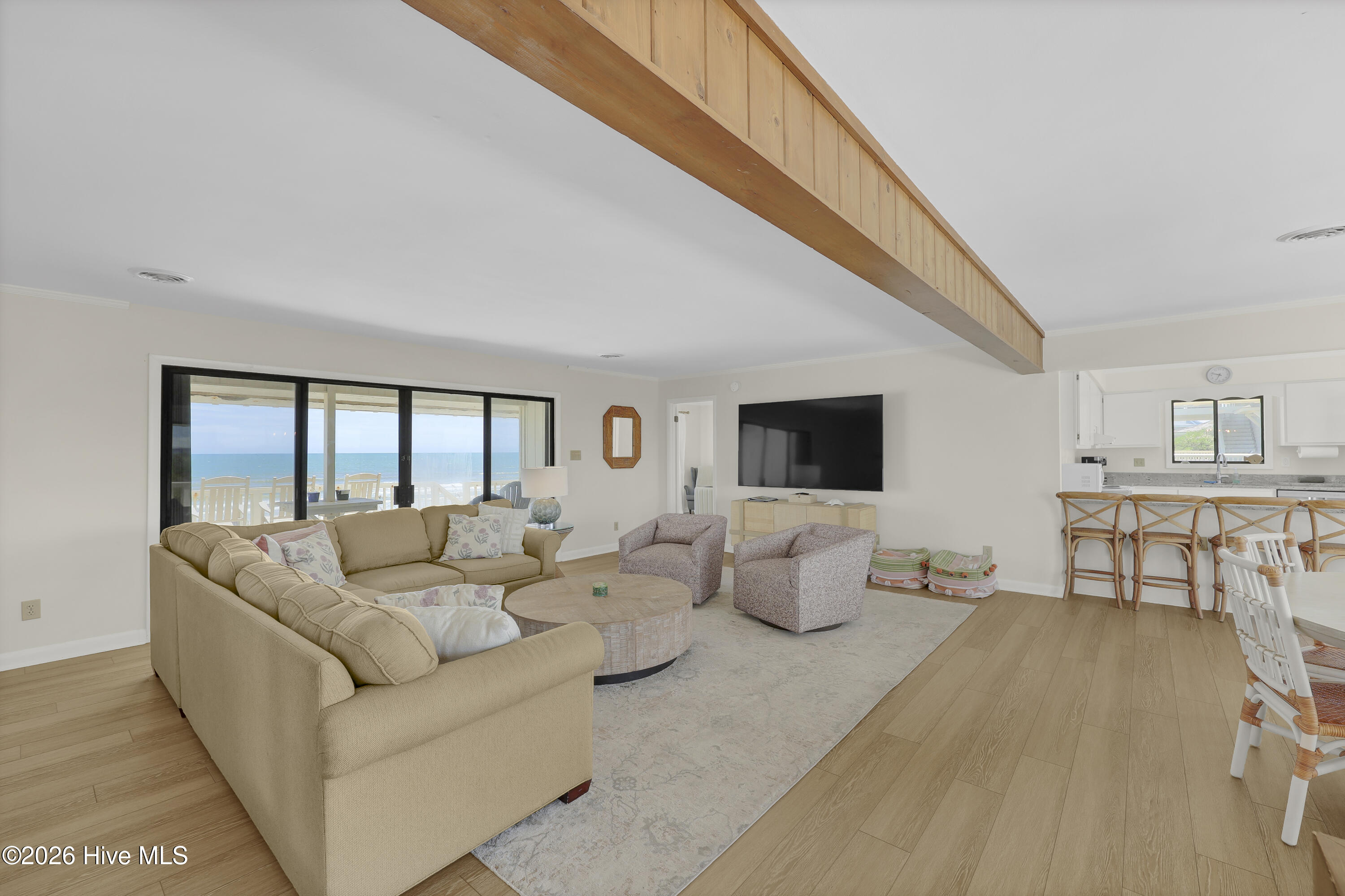 Living room with a beige sectional and ocean views through sliding glass doors.