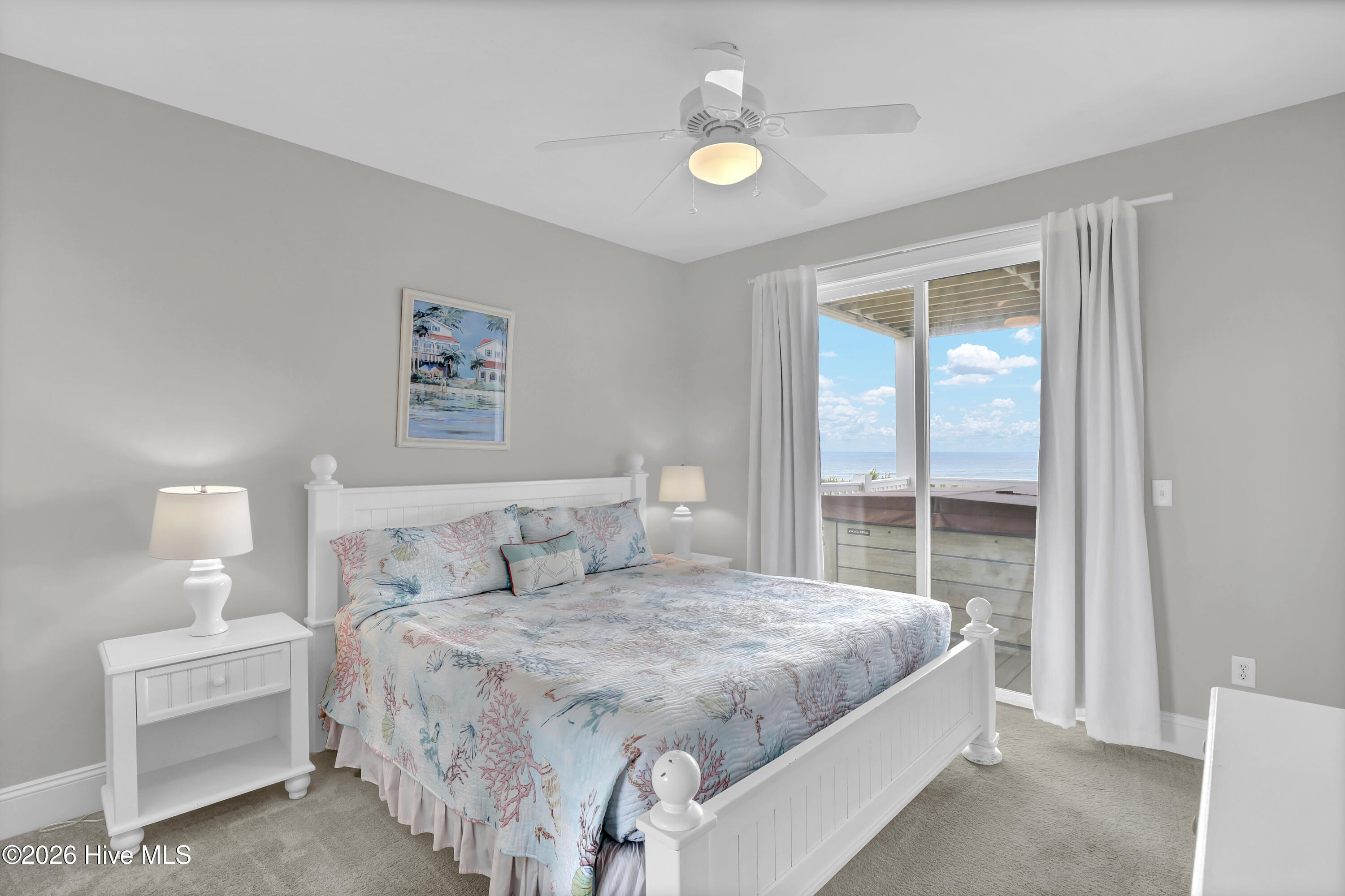 Furnished bedroom with coral-patterned bedding and sliding doors overlooking the ocean.