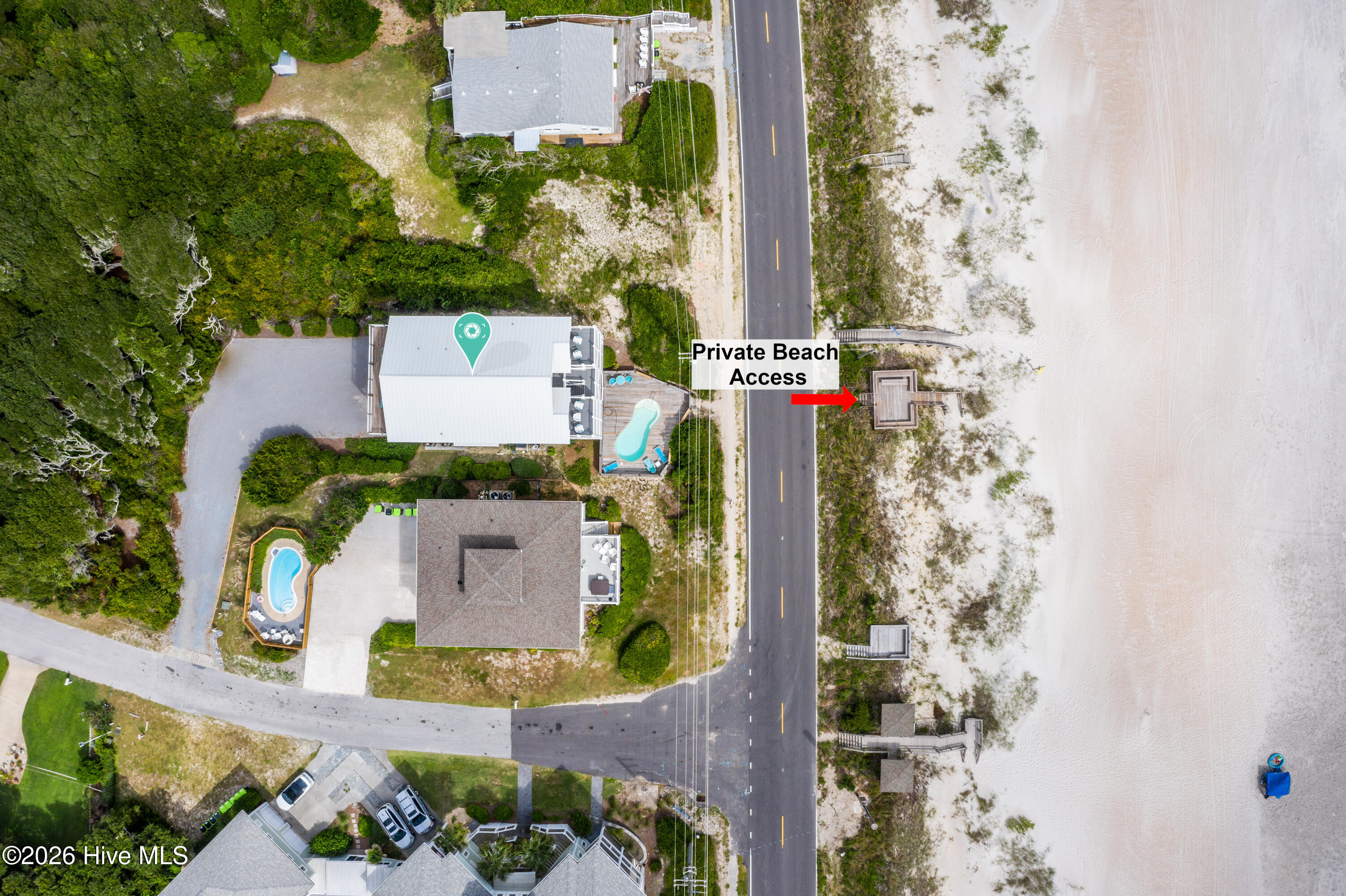 Aerial view of a coastal home with a pool and marked private beach access.