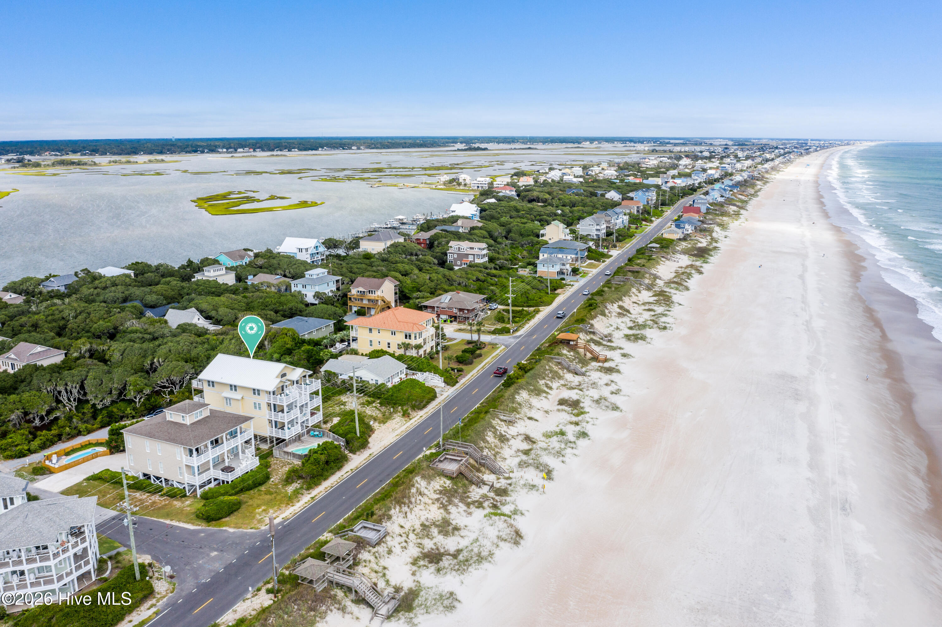 Aerial view of a coastal home beside the beach, road, and sound.