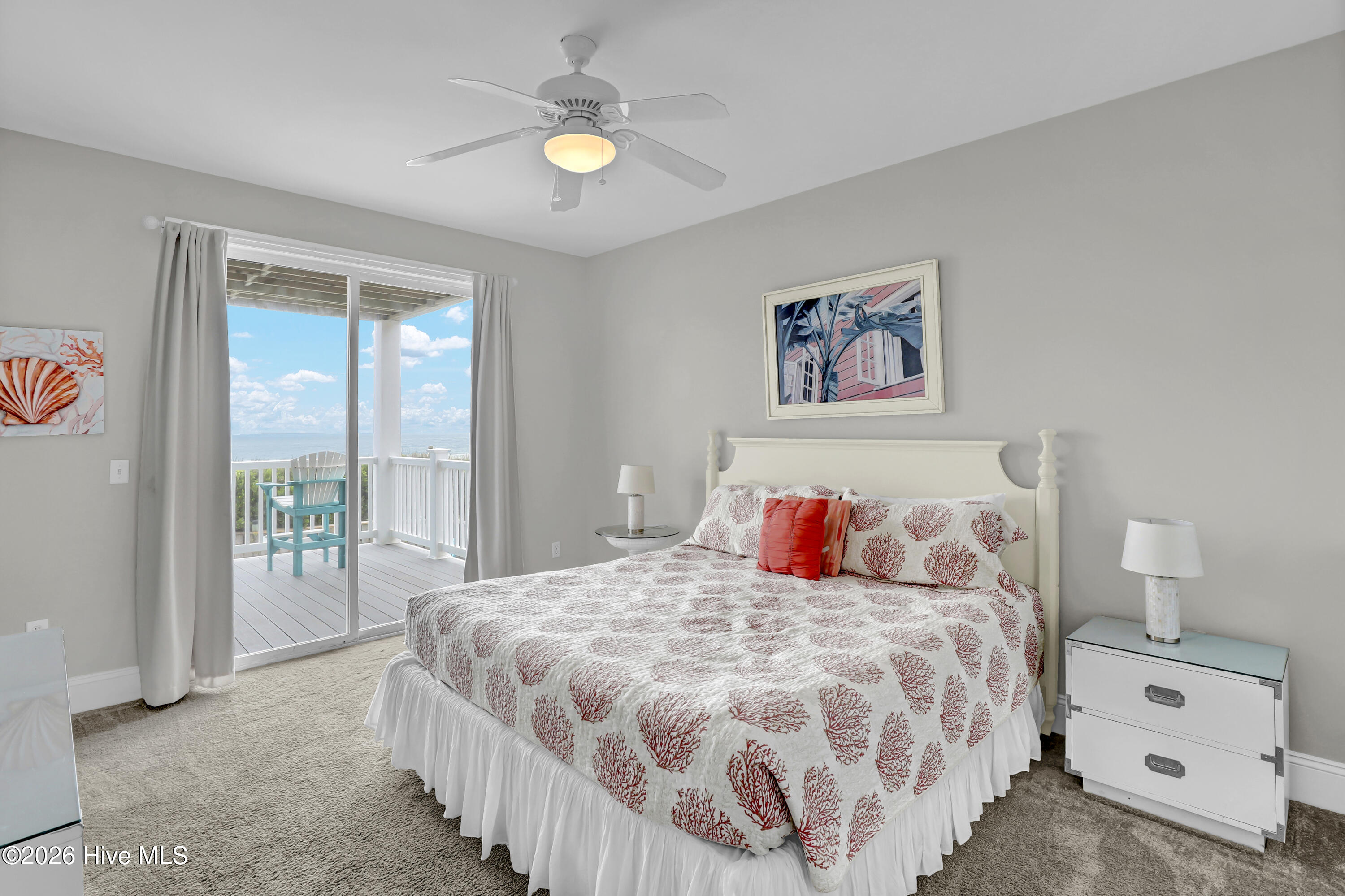 Bedroom with coral-patterned bedding and sliding doors opening to an ocean-view balcony.
