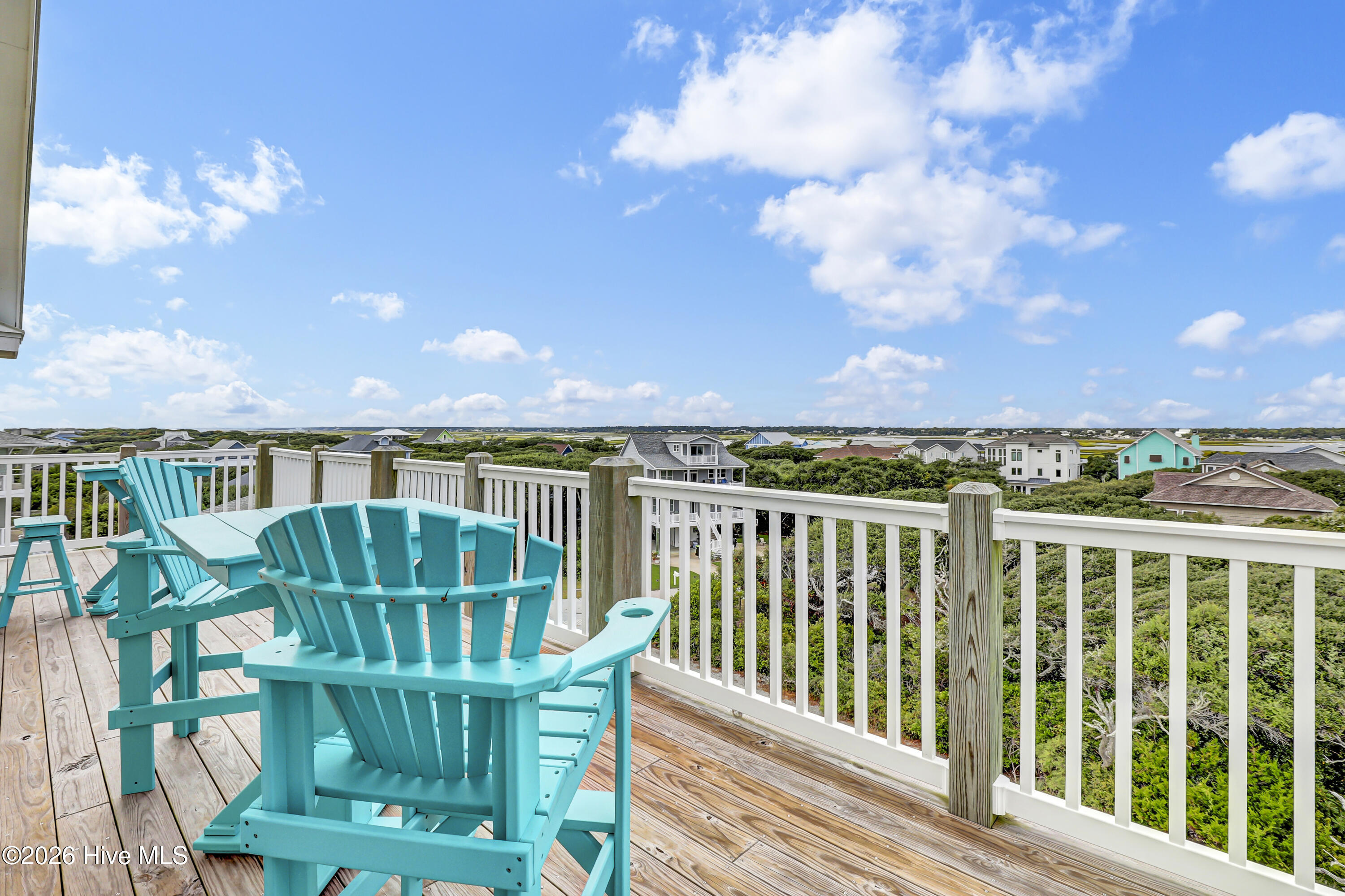 Deck with turquoise Adirondack chairs overlooking neighboring coastal homes.