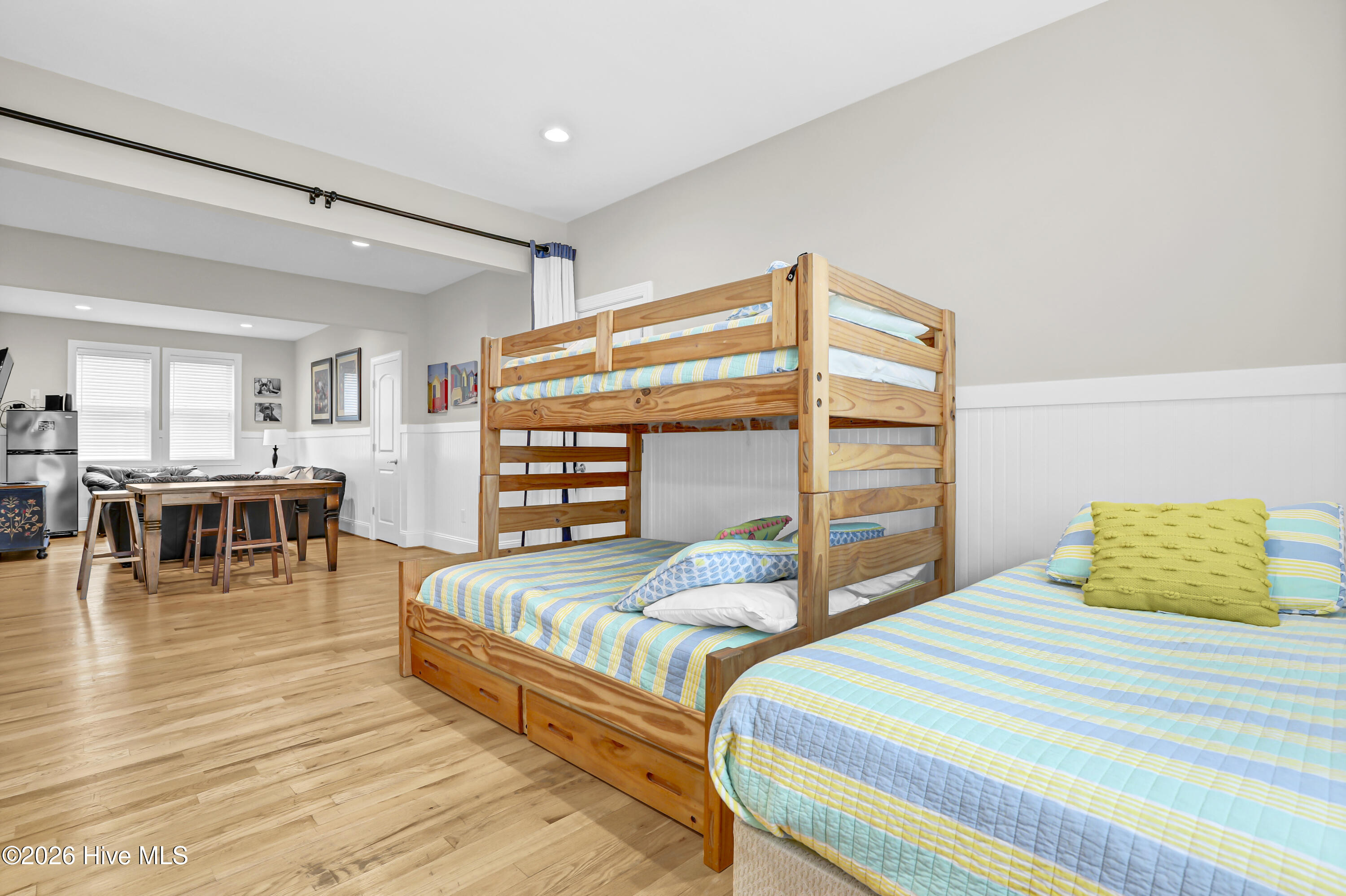 Bedroom with a wooden bunk bed, a separate bed, striped bedding, and hardwood floors.