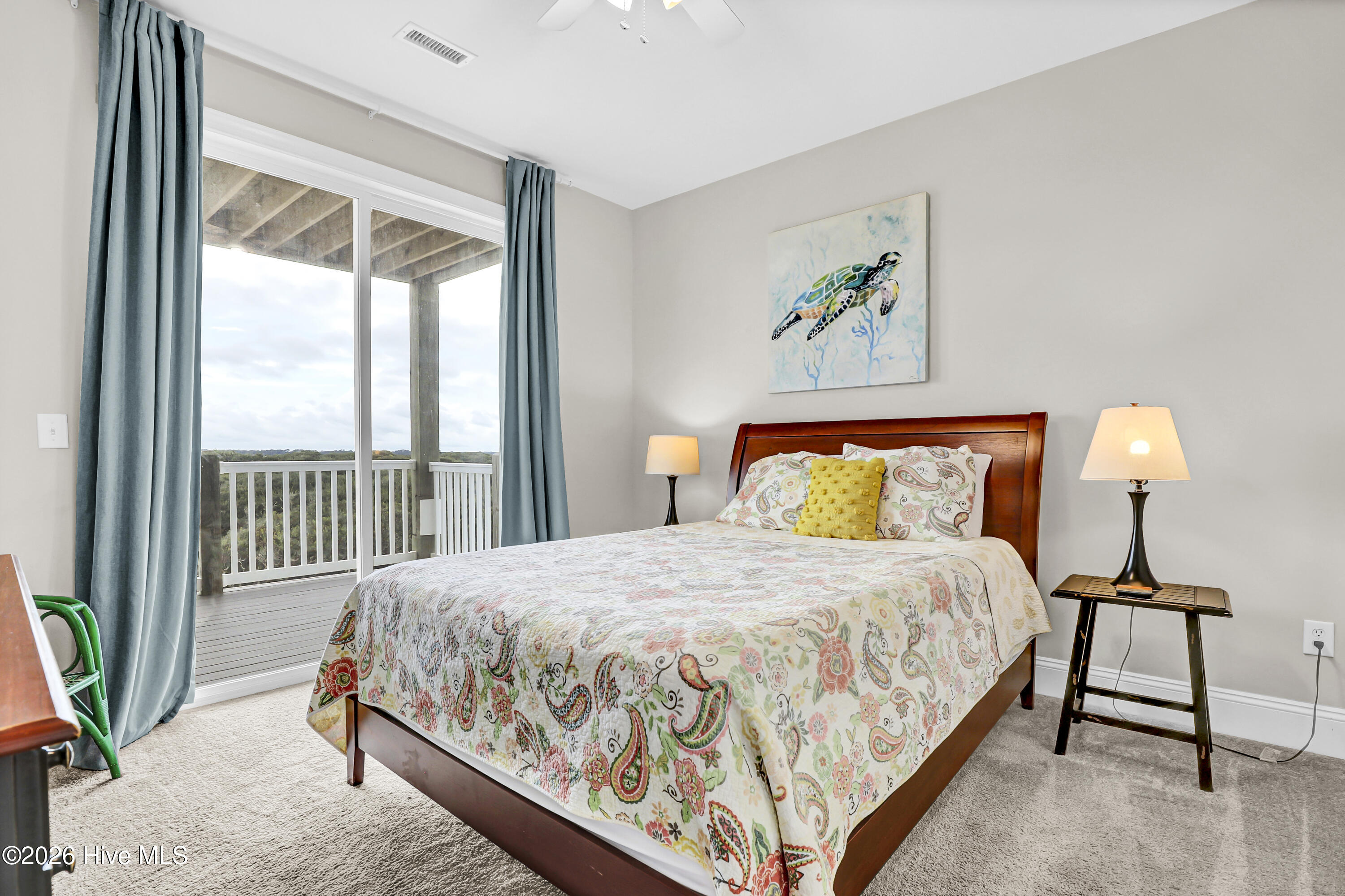 Bedroom with patterned bedding and sliding doors opening to a covered balcony.