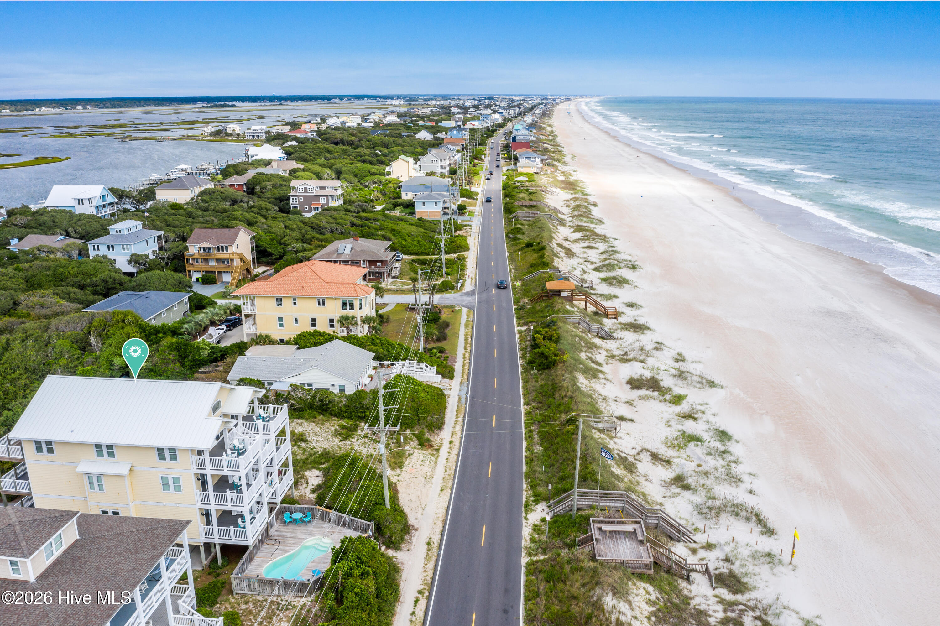 Aerial view of a marked coastal home with a pool, beside the beach and oceanfront road.