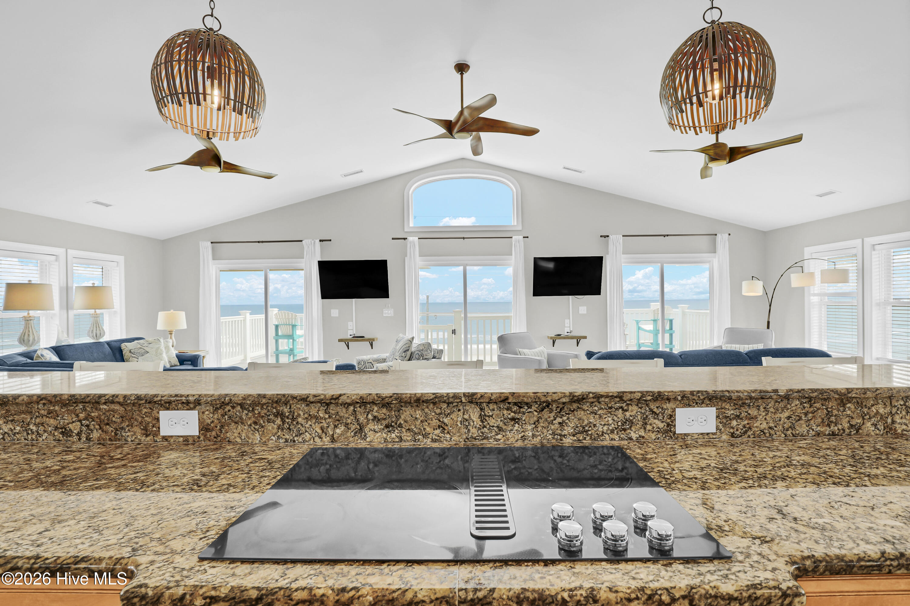 Kitchen island with granite counters overlooks a furnished living room and ocean-facing windows.