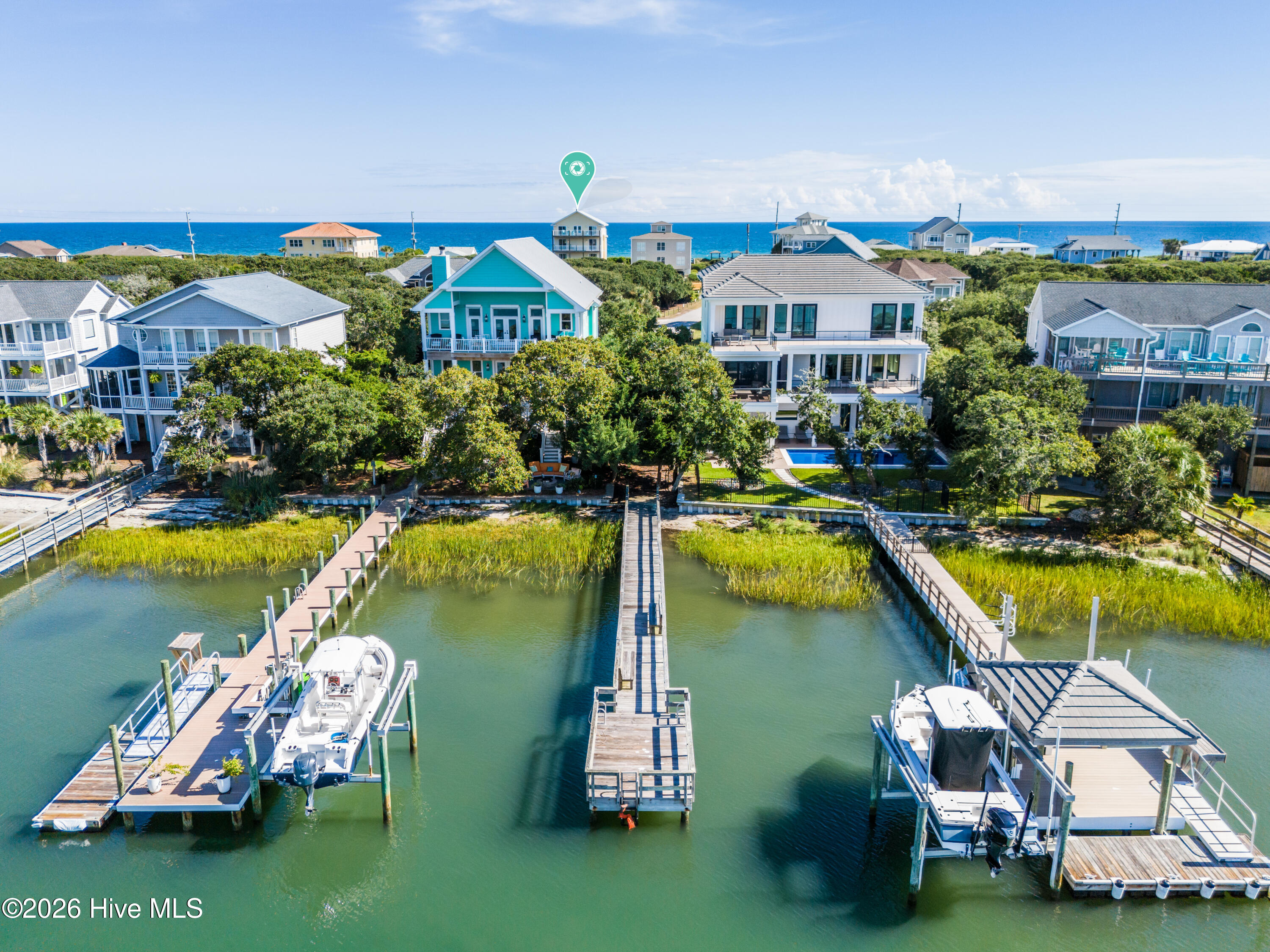 Aerial view of coastal homes and docks, with boats in the foreground and the ocean beyond.