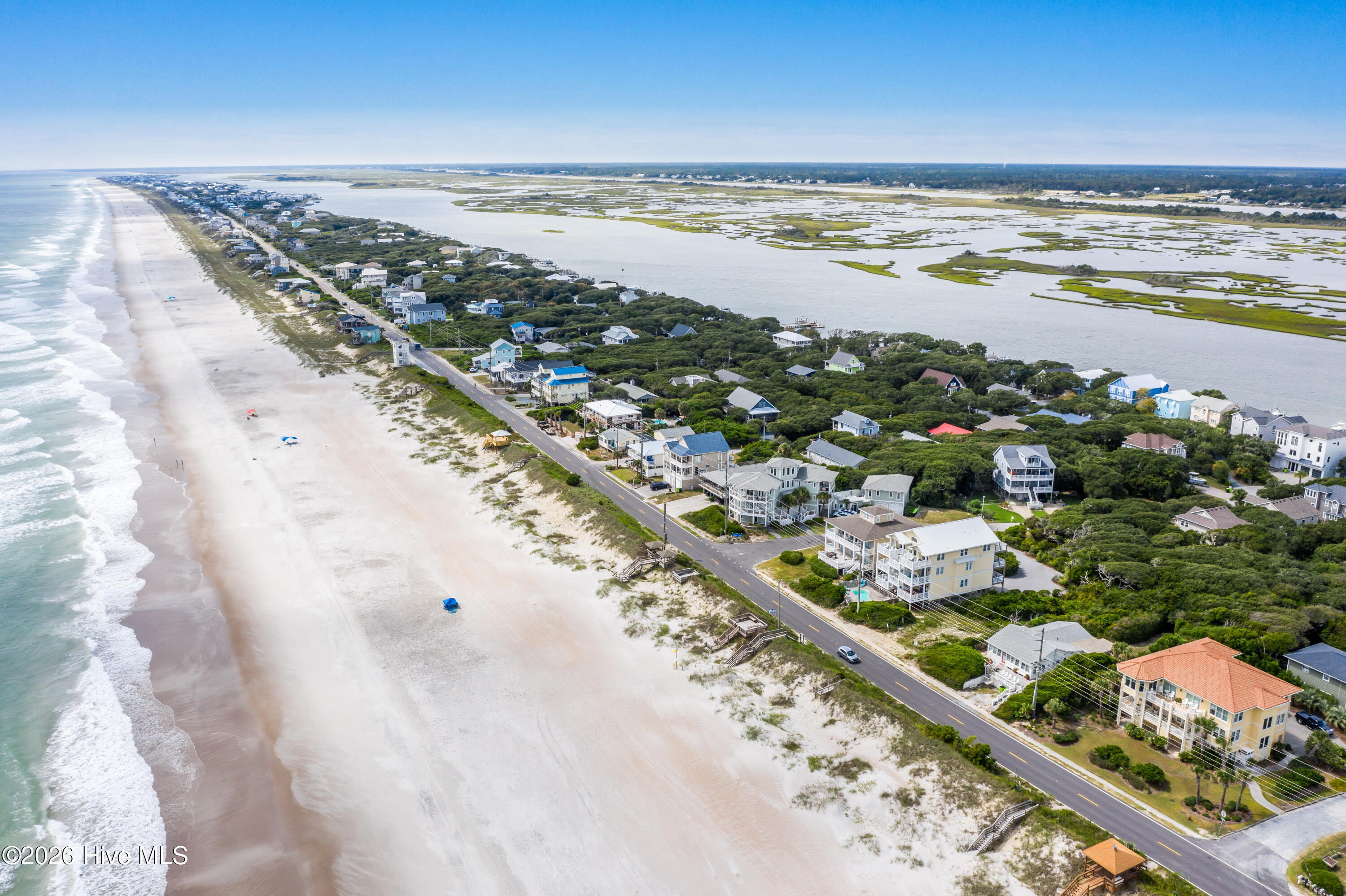 Aerial view of beachfront homes between the ocean beach and a marshy inlet.