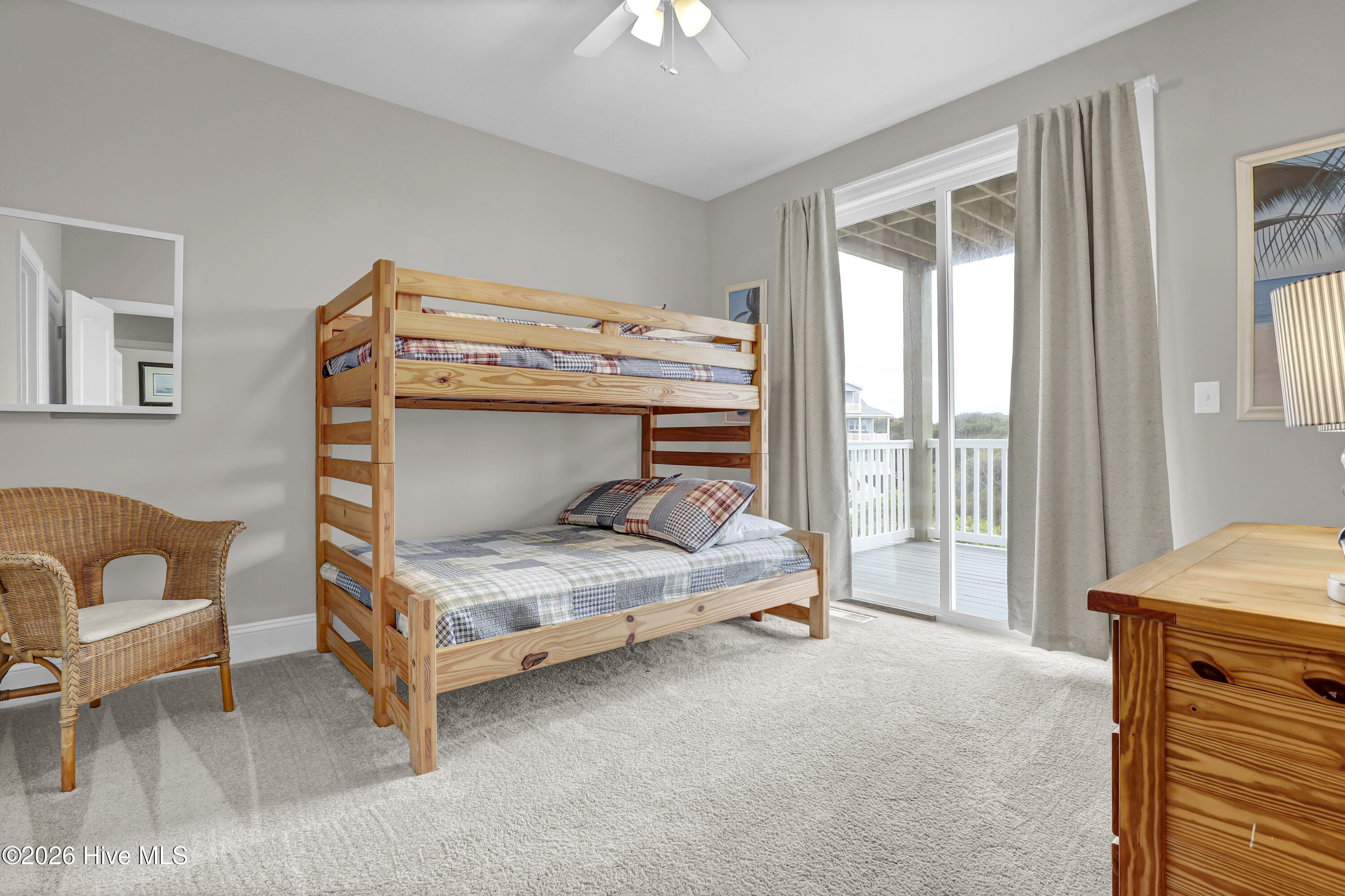 Bedroom with a wooden bunk bed beside sliding glass doors to a covered balcony.