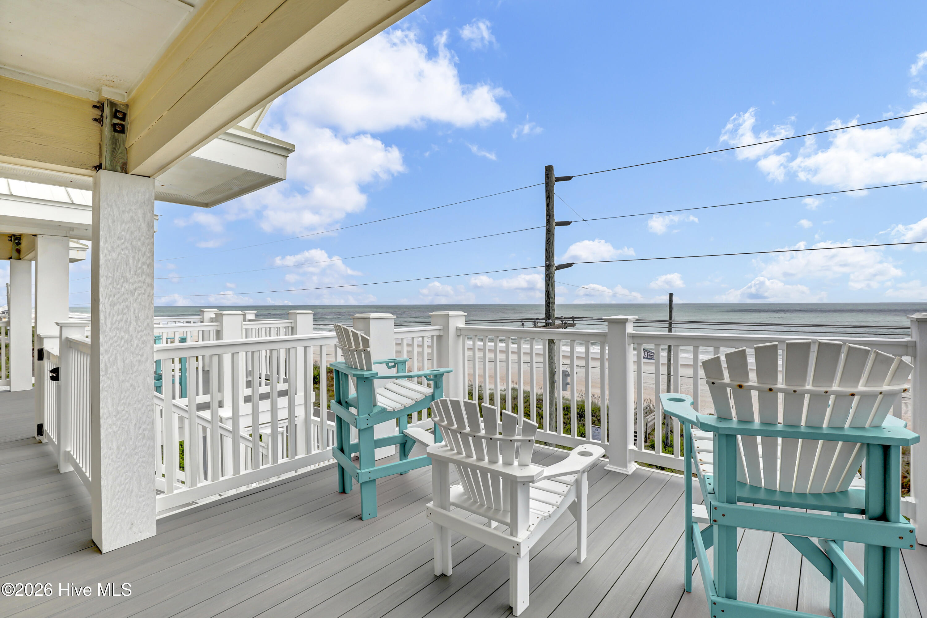 Oceanfront deck with turquoise and white Adirondack chairs overlooking the beach and ocean.