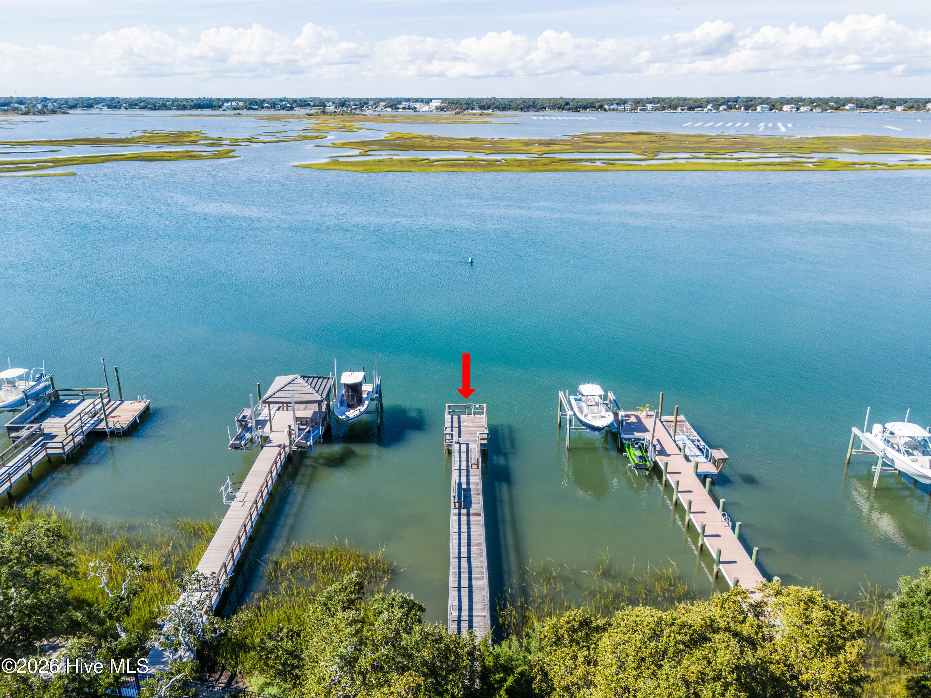 Aerial waterfront view with a red arrow pointing to a long dock among neighboring boat docks.