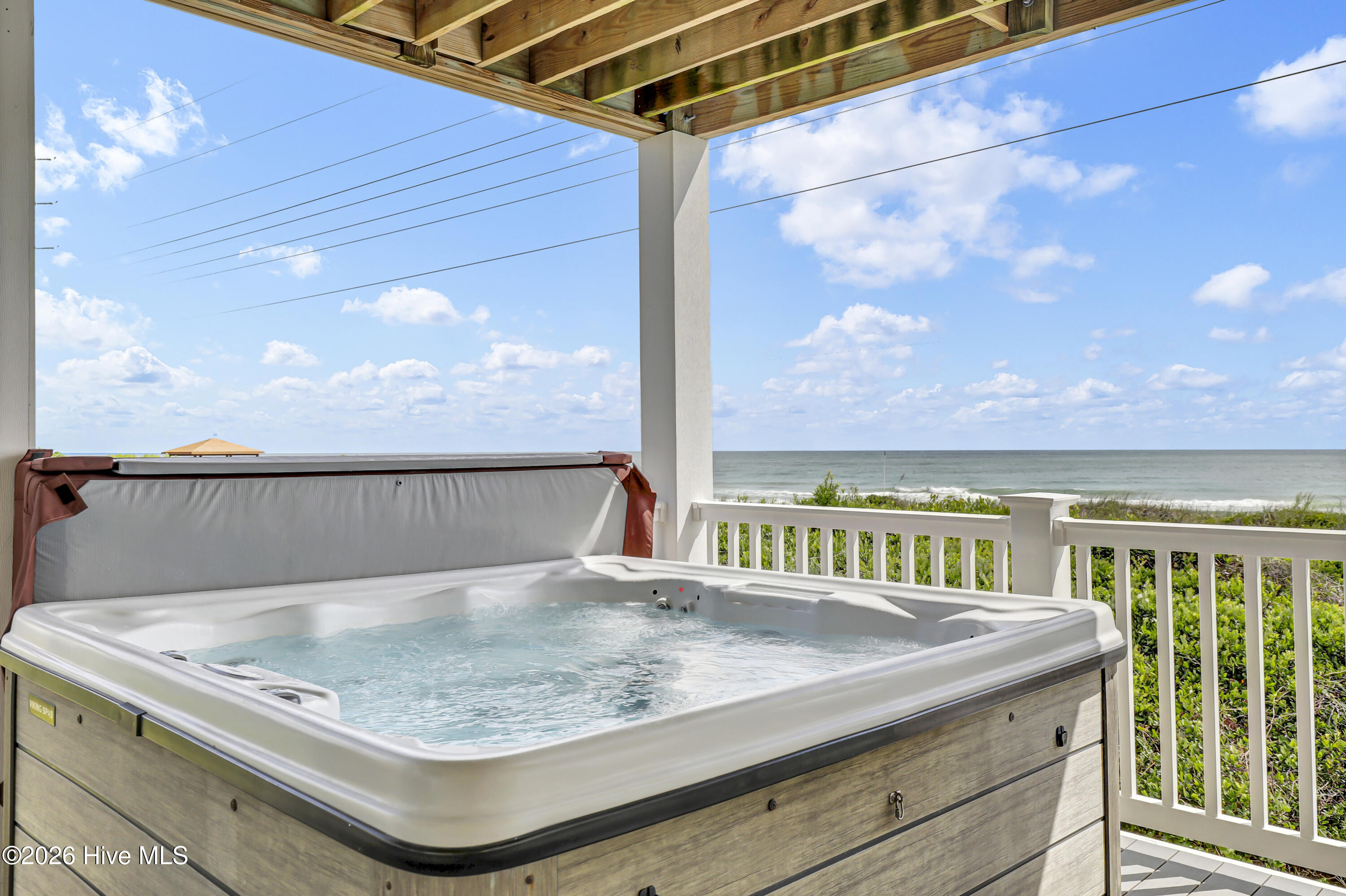 Hot tub on a covered deck overlooking the ocean.