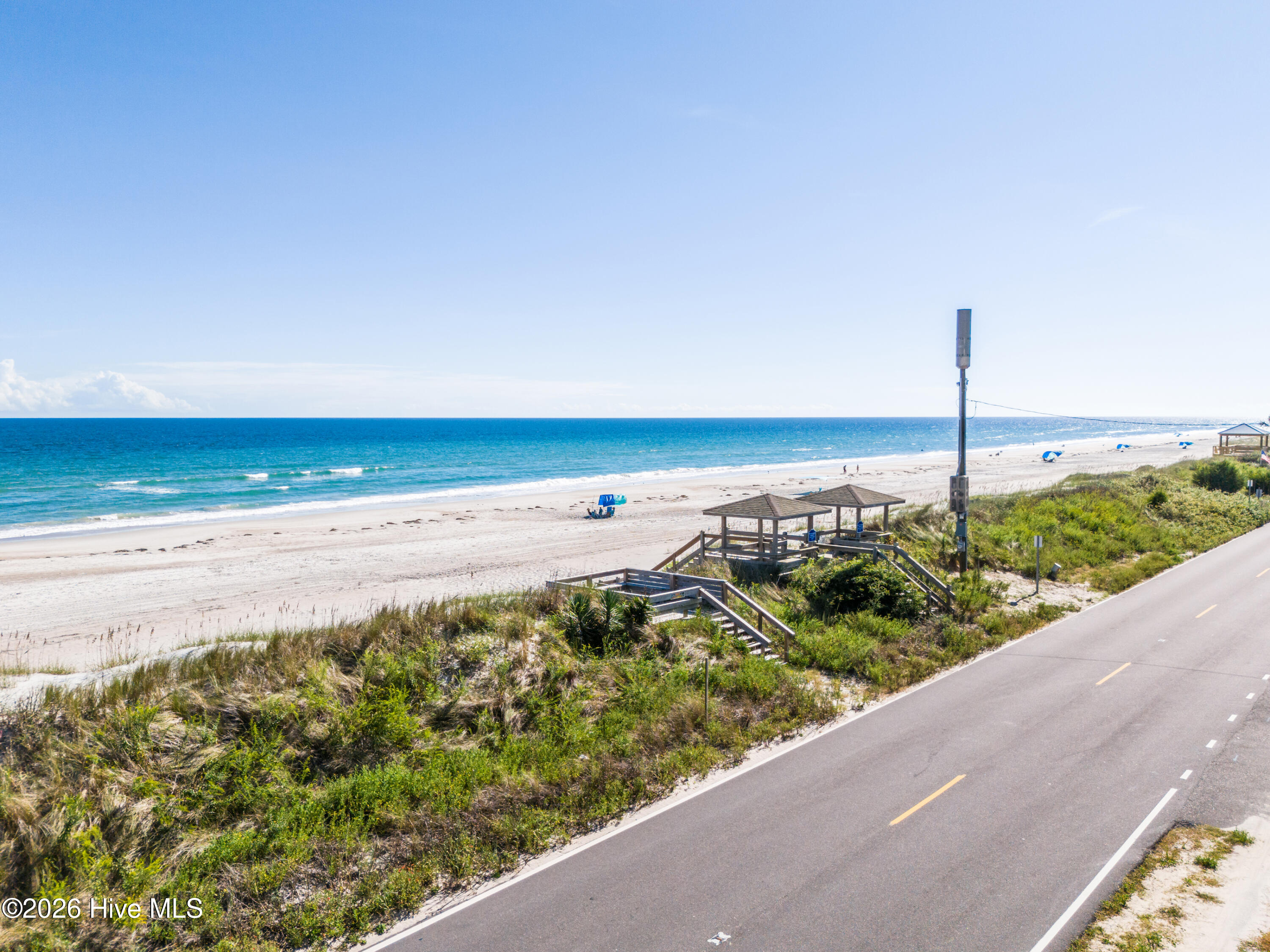 Surf City beach and ocean beside a coastal road, with dune grasses and wooden beach access platforms.