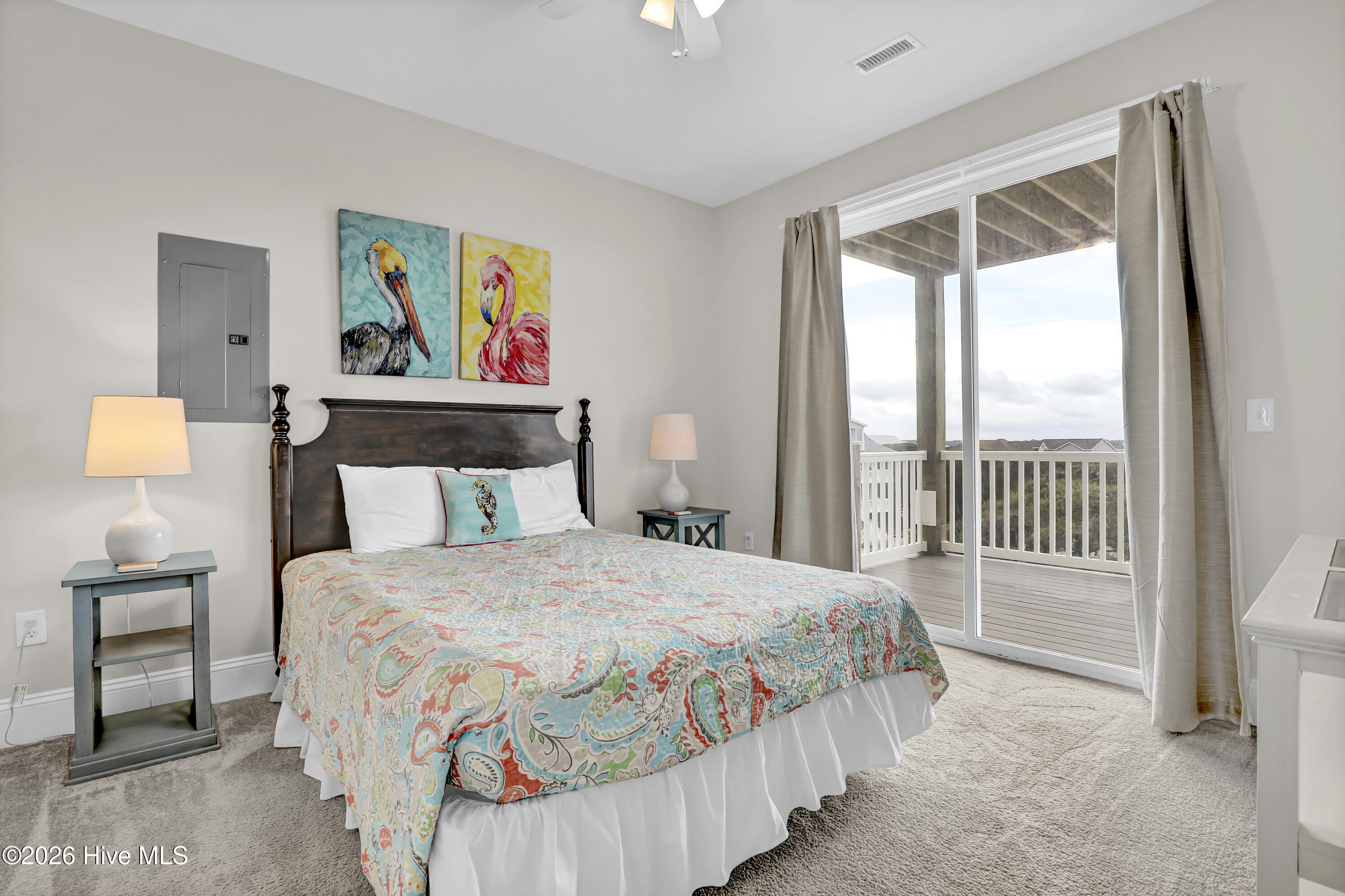 Bedroom with a colorful patterned quilt and sliding glass doors opening onto a covered balcony.