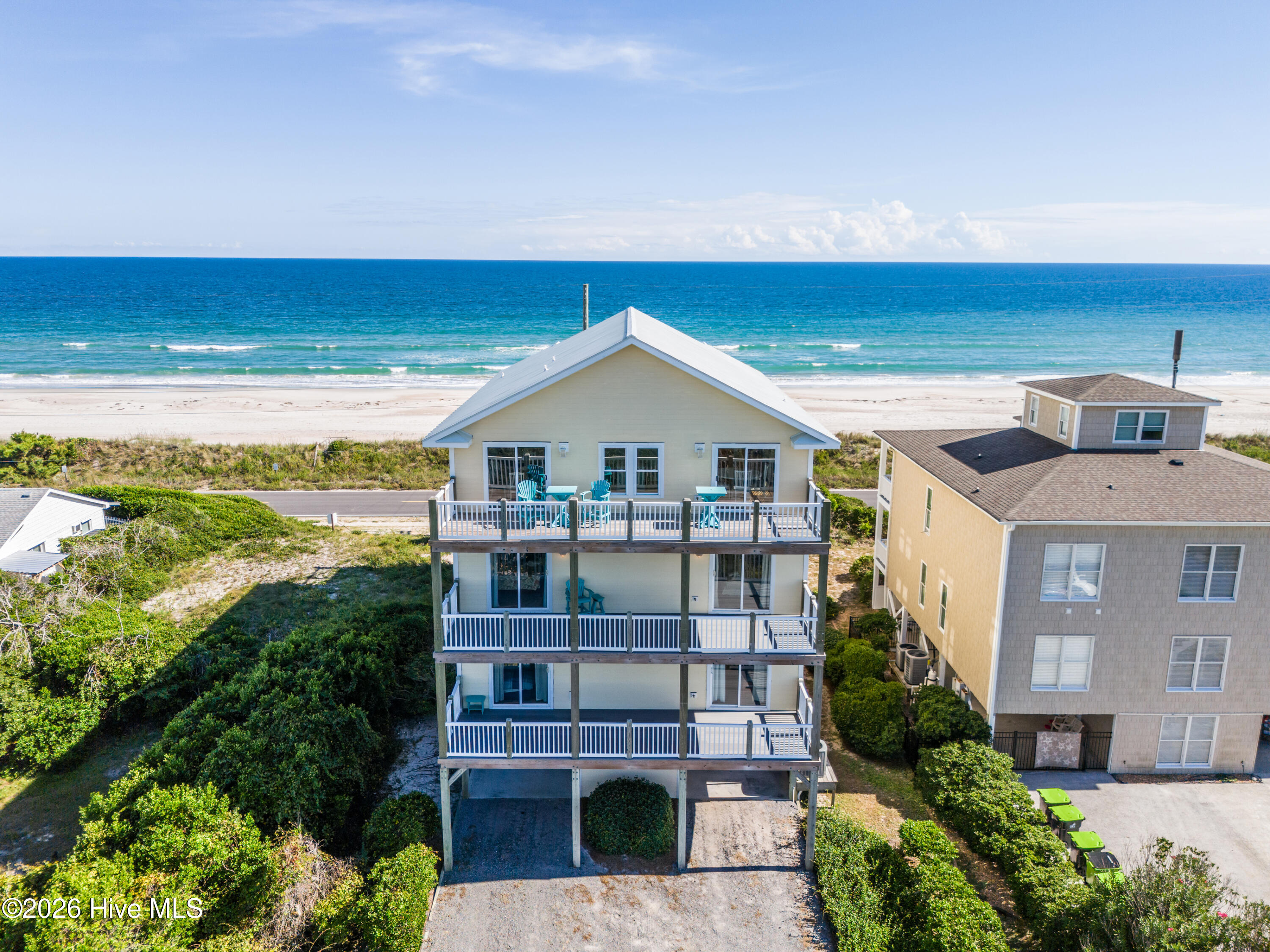 Elevated beach house with stacked decks overlooking a sandy beach and ocean.