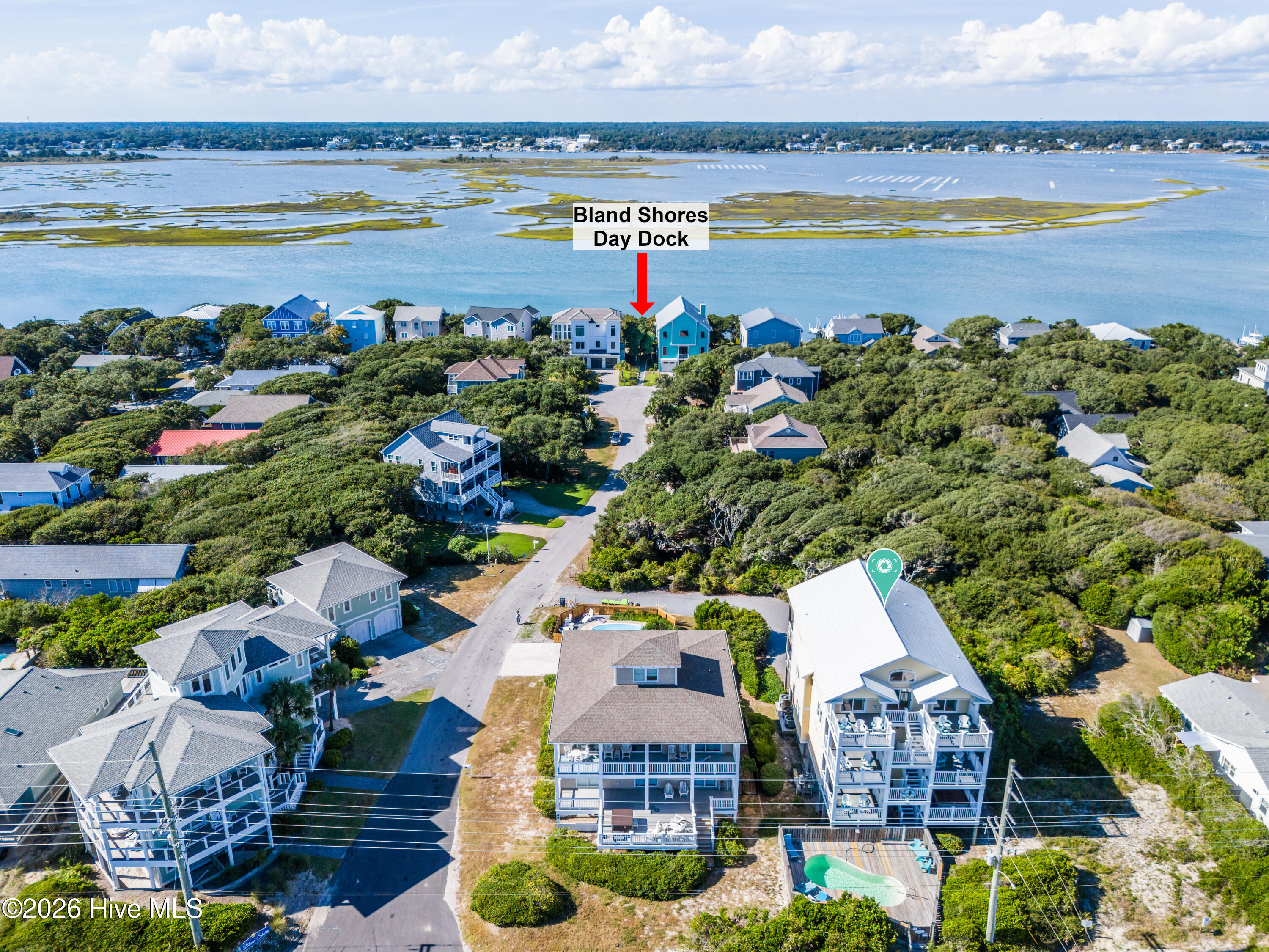 Aerial view of the marked coastal home and surrounding neighborhood beside a tidal waterway.