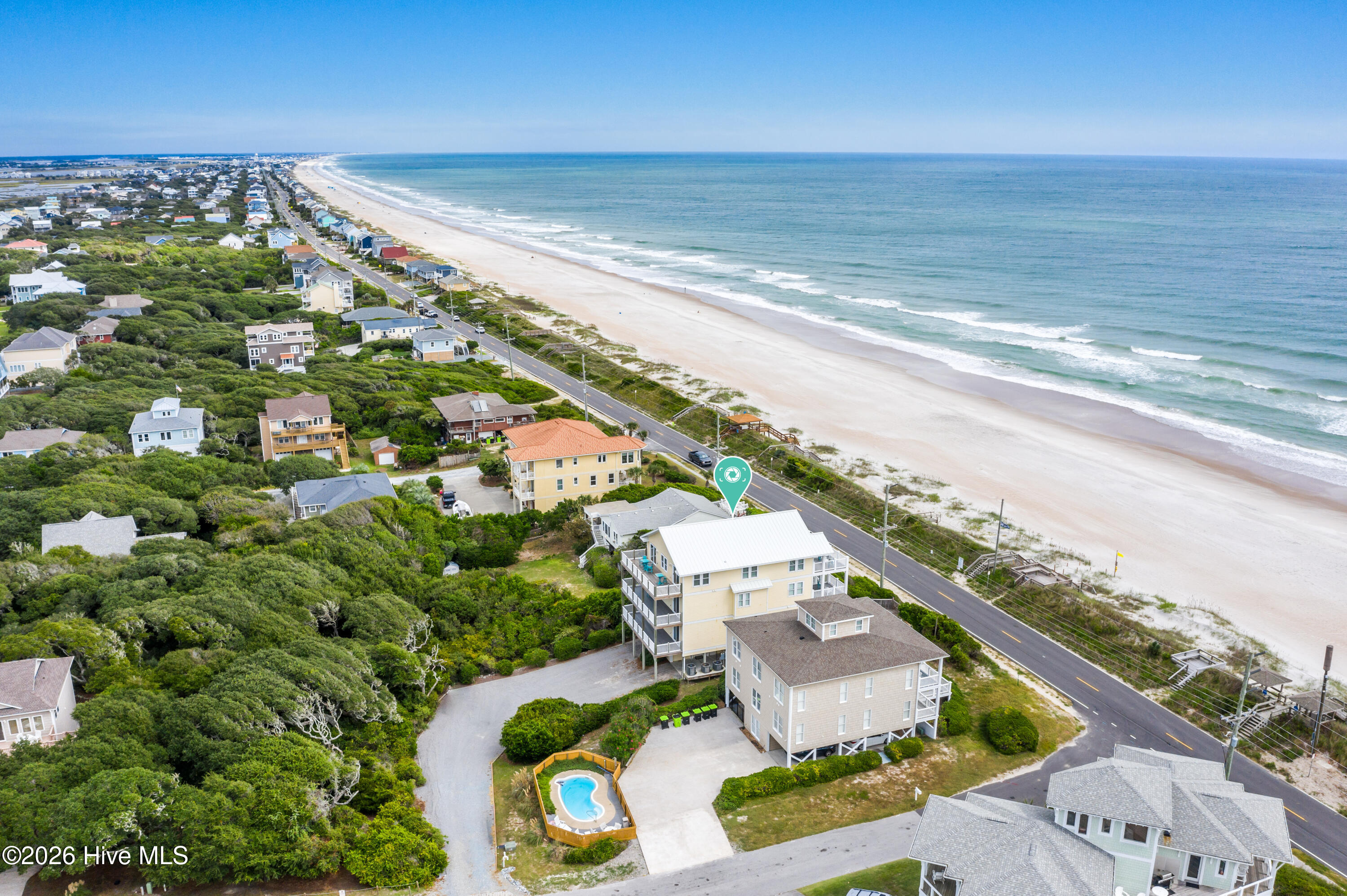 Aerial view of coastal homes, with the marked property, beach, and private pool.