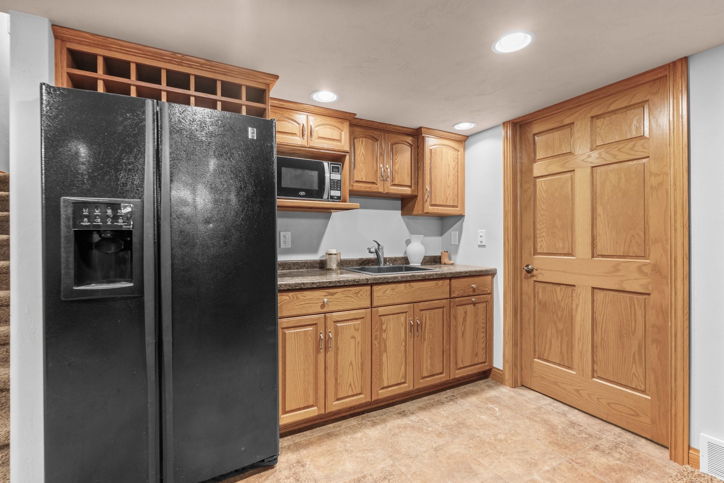 Kitchen with oak cabinets, black refrigerator, built-in microwave, and sink.